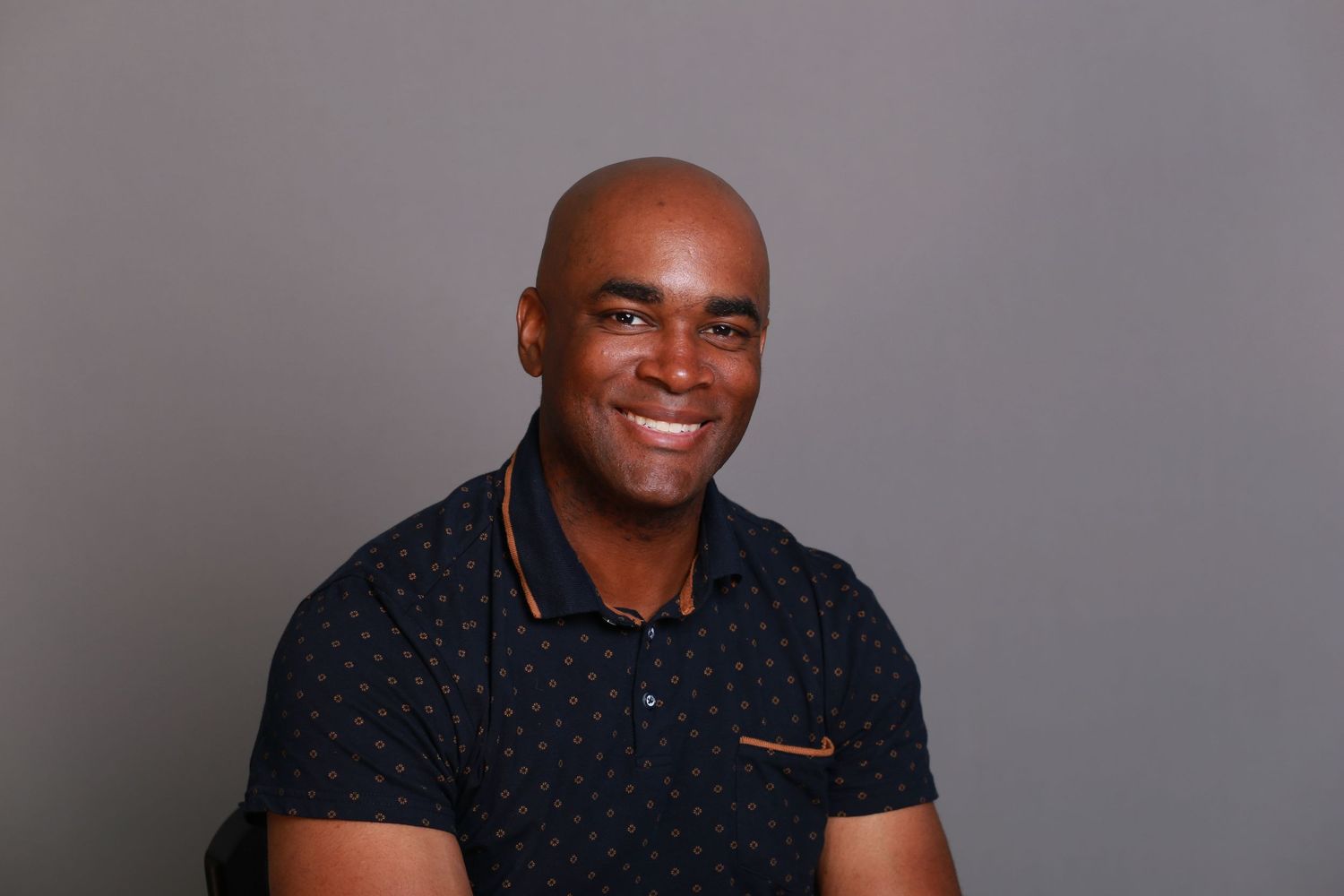 Professional headshots against grey background showing warm expressions.