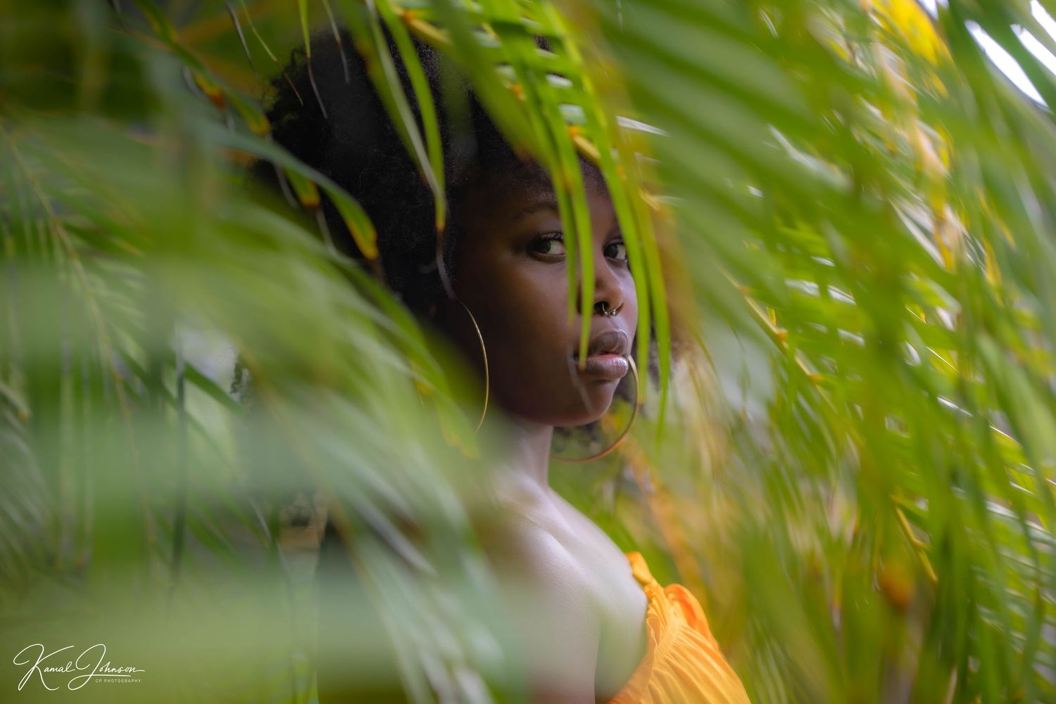 Artistic portrait through tropical foliage creating a natural frame effect.