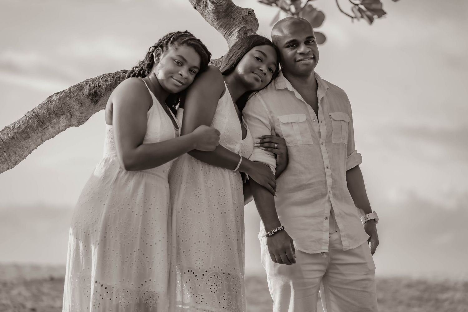 Group poses for black and white portrait against ocean backdrop.