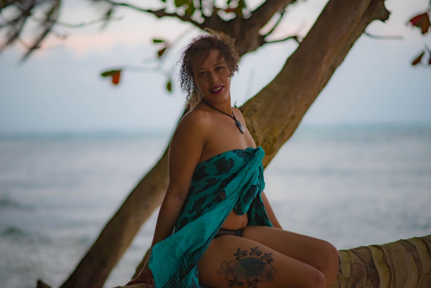 Beachside portrait at sunset with turquoise swimwear against ocean backdrop.