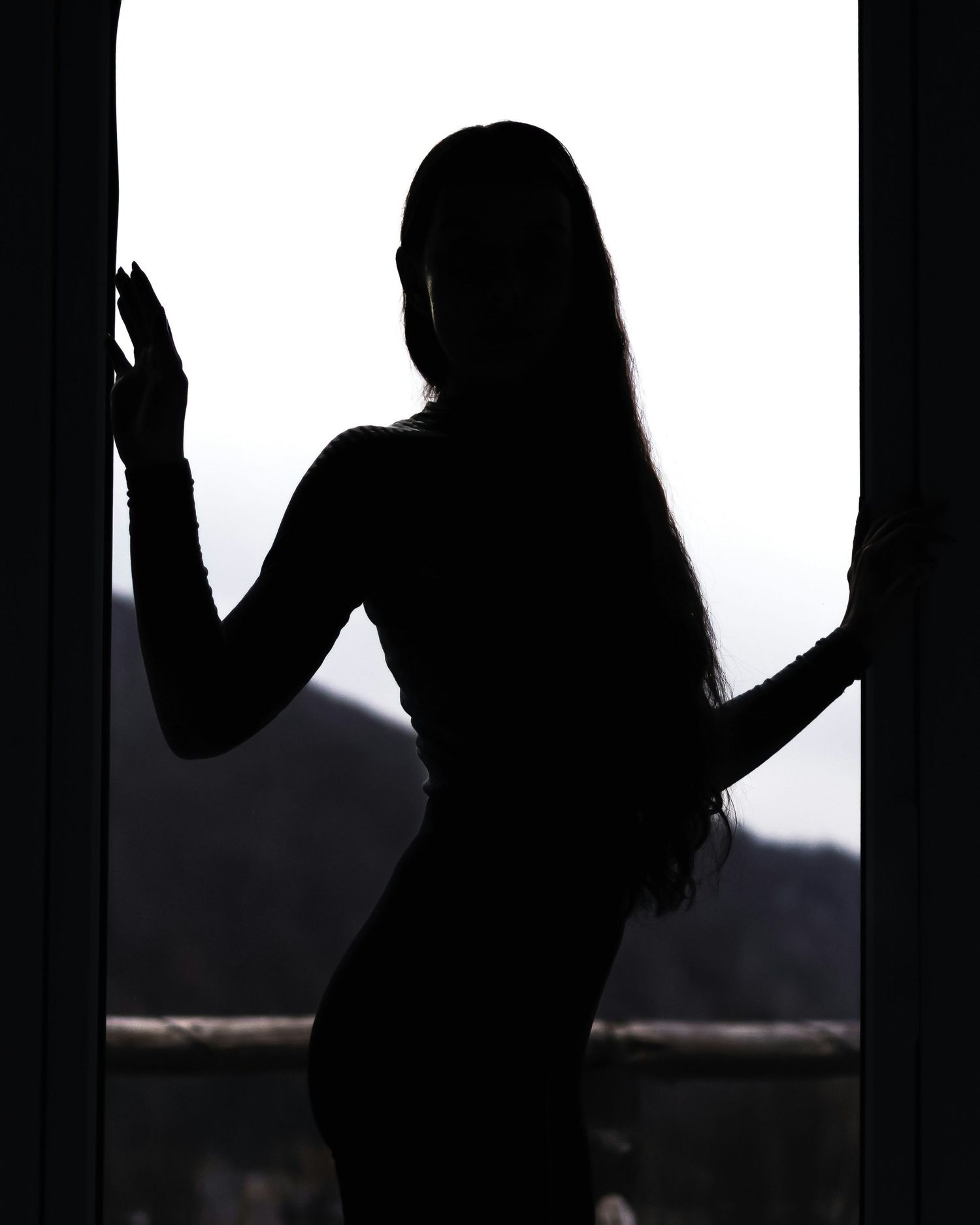 Silhouetted figure with raised arms against a bright window creating a dramatic shadow effect.
