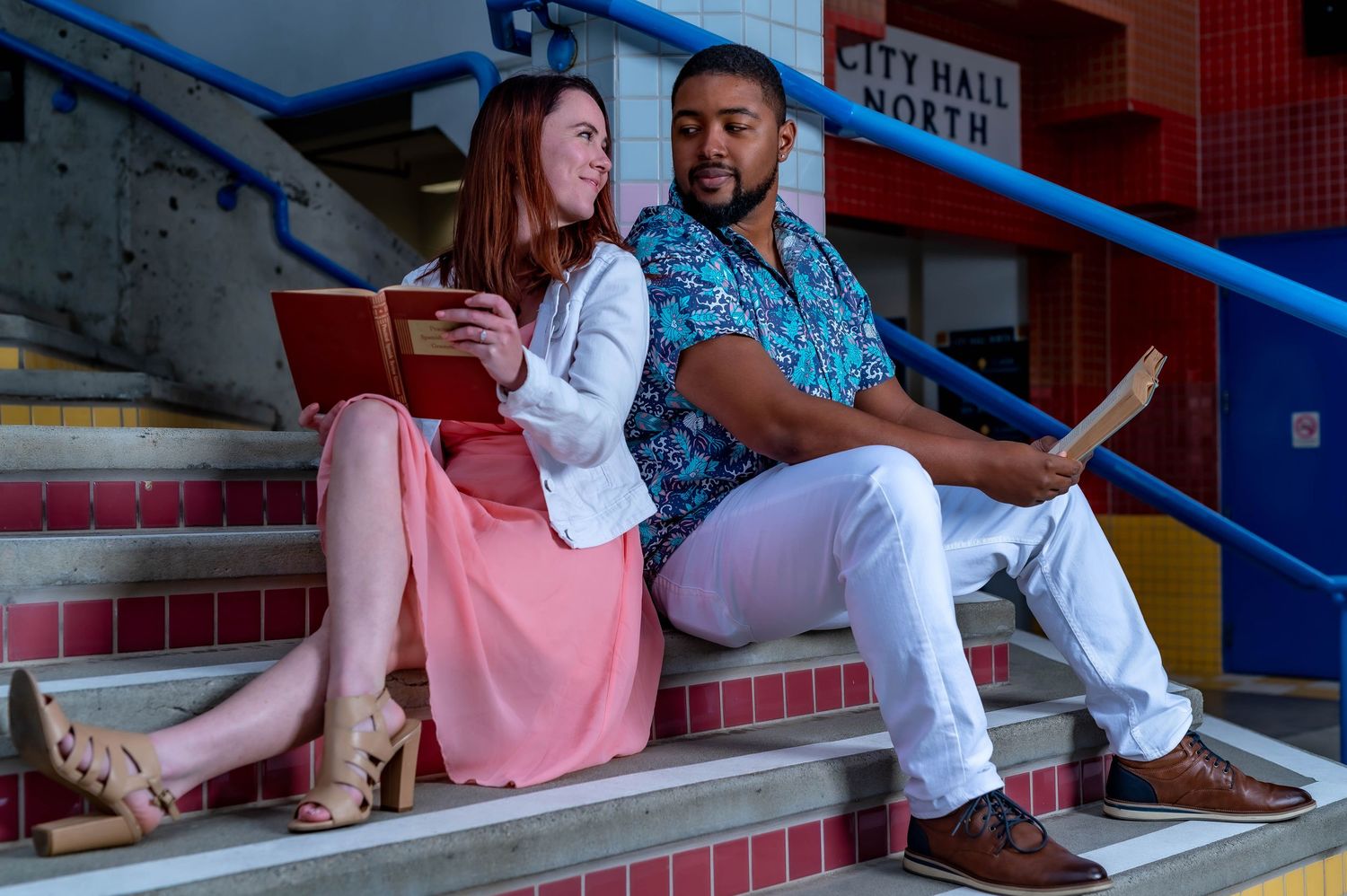 Couple sitting on red and white bleacher seats at a sports venue.
