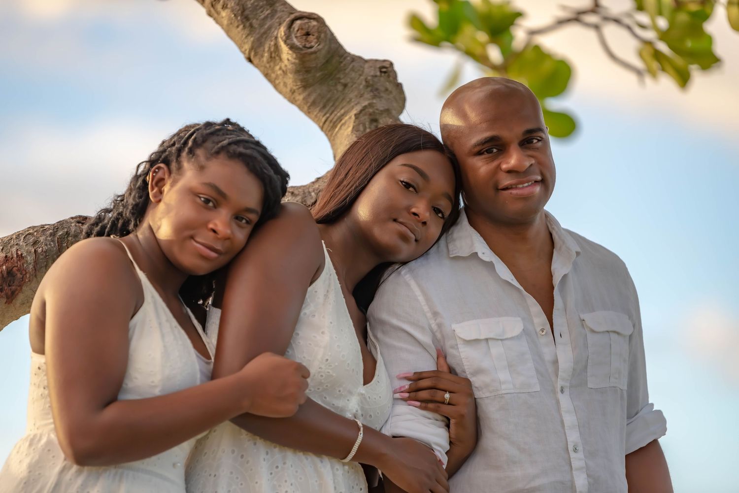 Family group portraits on beach with ocean waves and blue sky in background.
