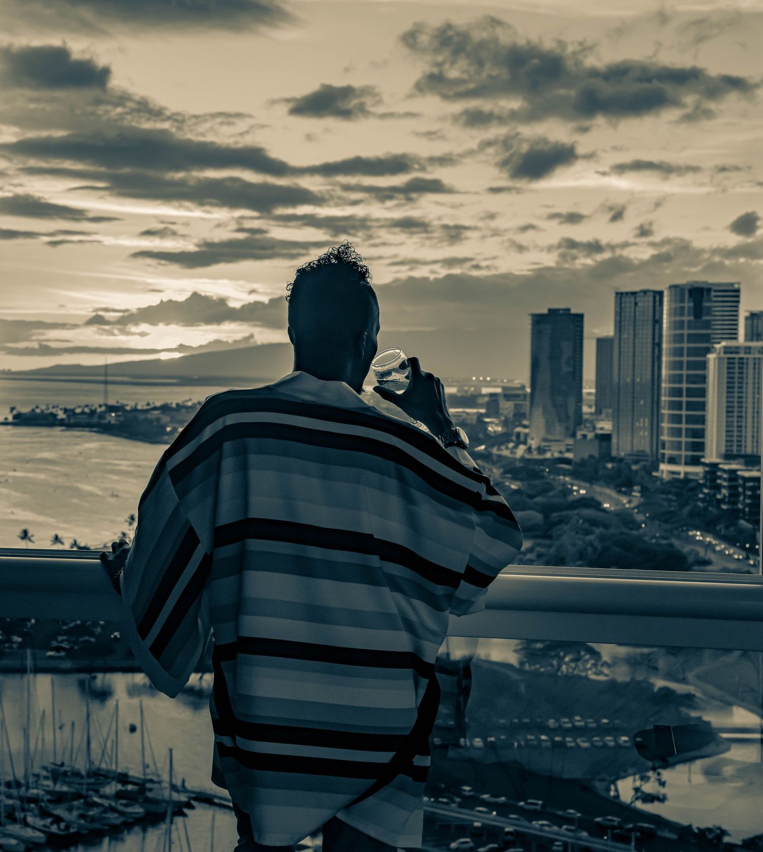 Dramatic cityscape silhouette against cloudy sky with modern buildings in background.