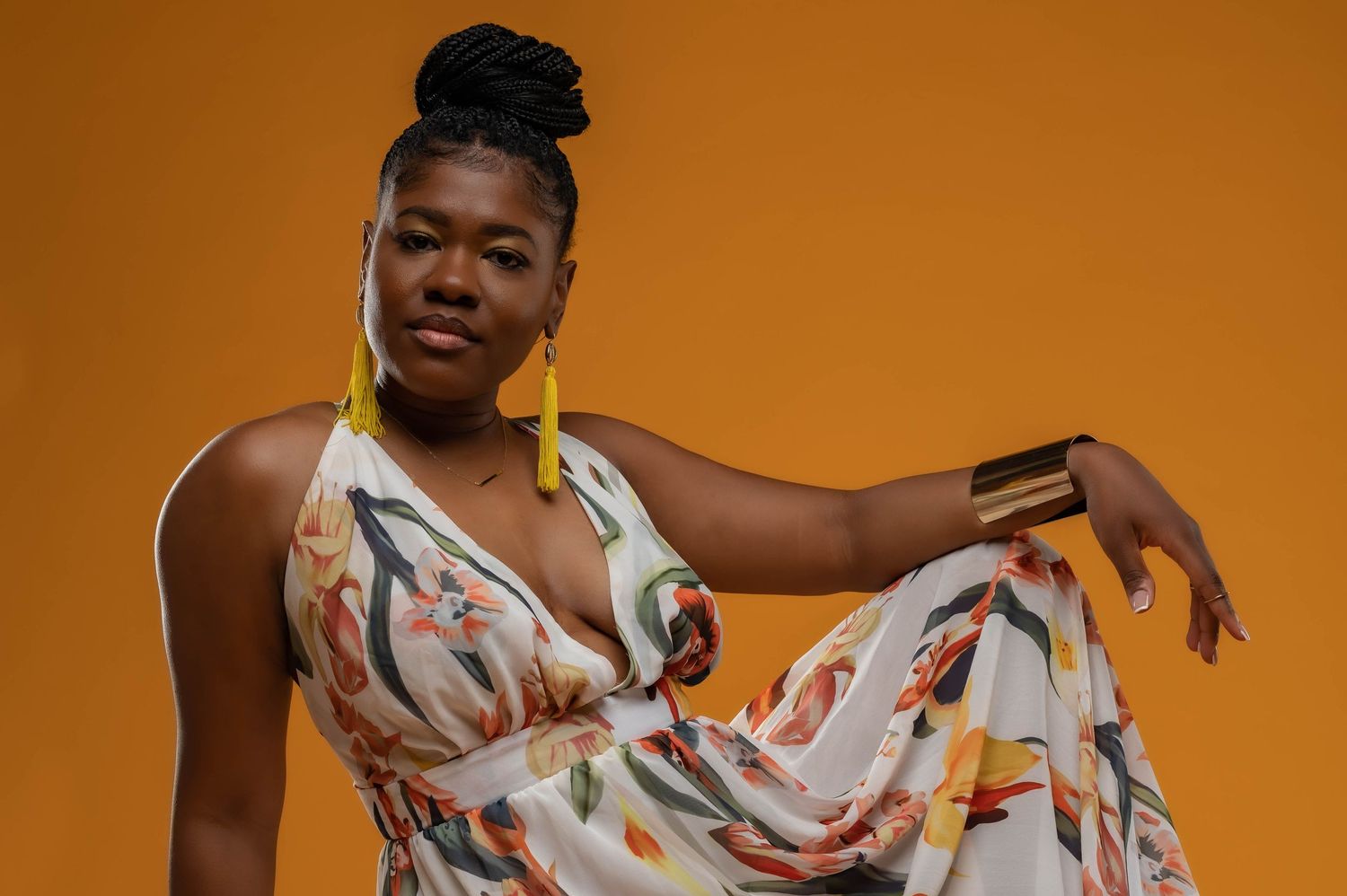 Fashion portrait against orange background wearing flowing floral dress.