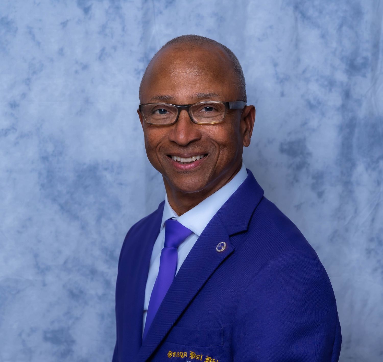 Professional headshot series featuring navy suit and purple tie against studio backdrop.