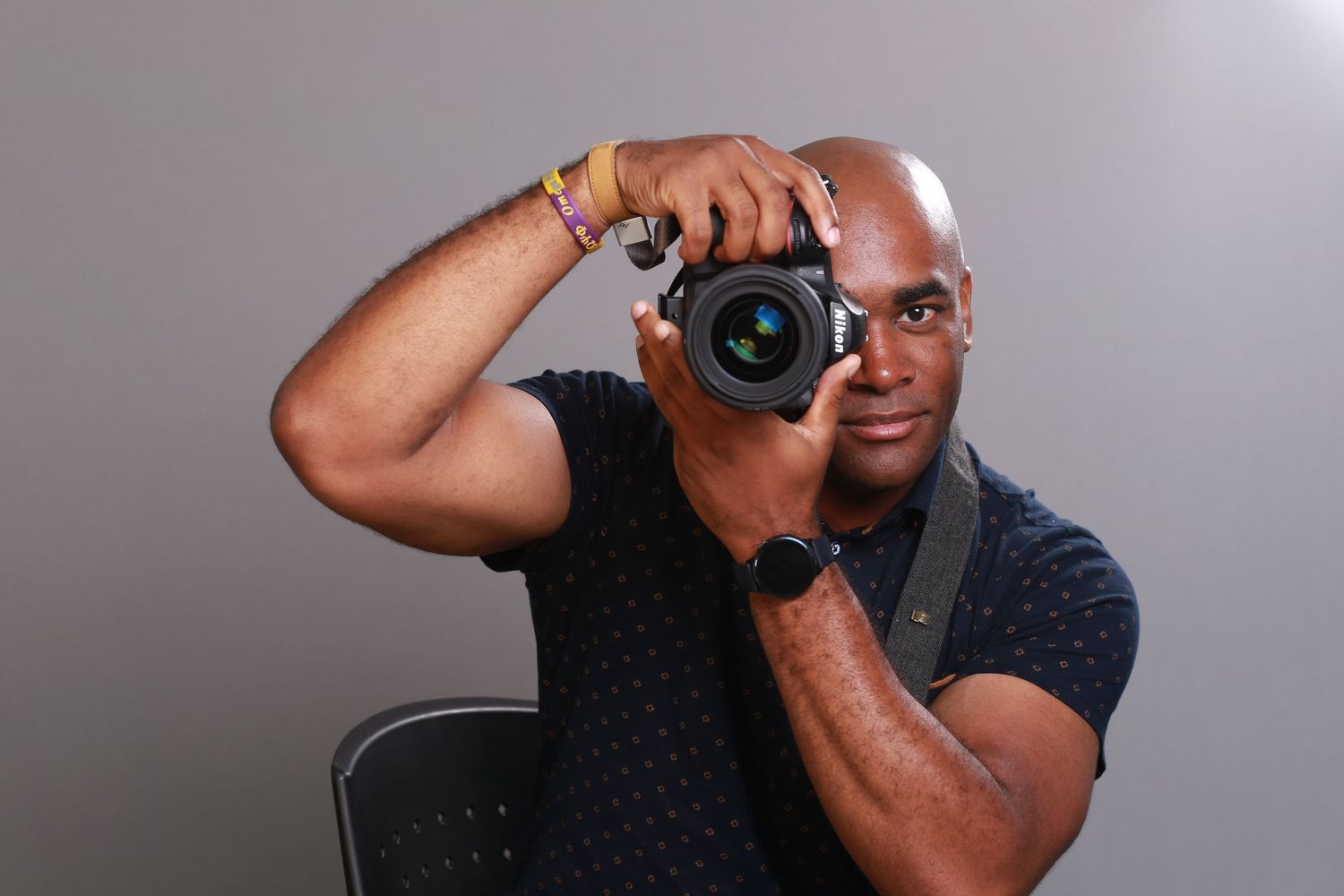 A photographer in a dark shirt holds up a professional camera to take a photo.