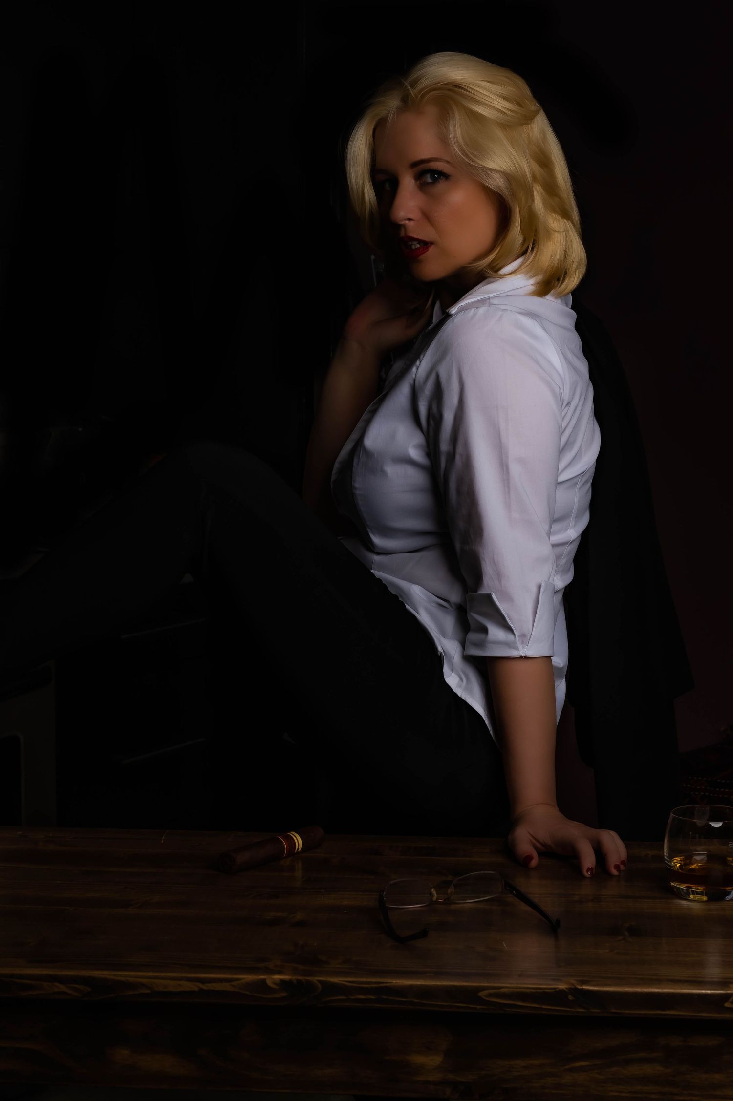 Moody portrait series in white blouse against dark background with dramatic lighting.