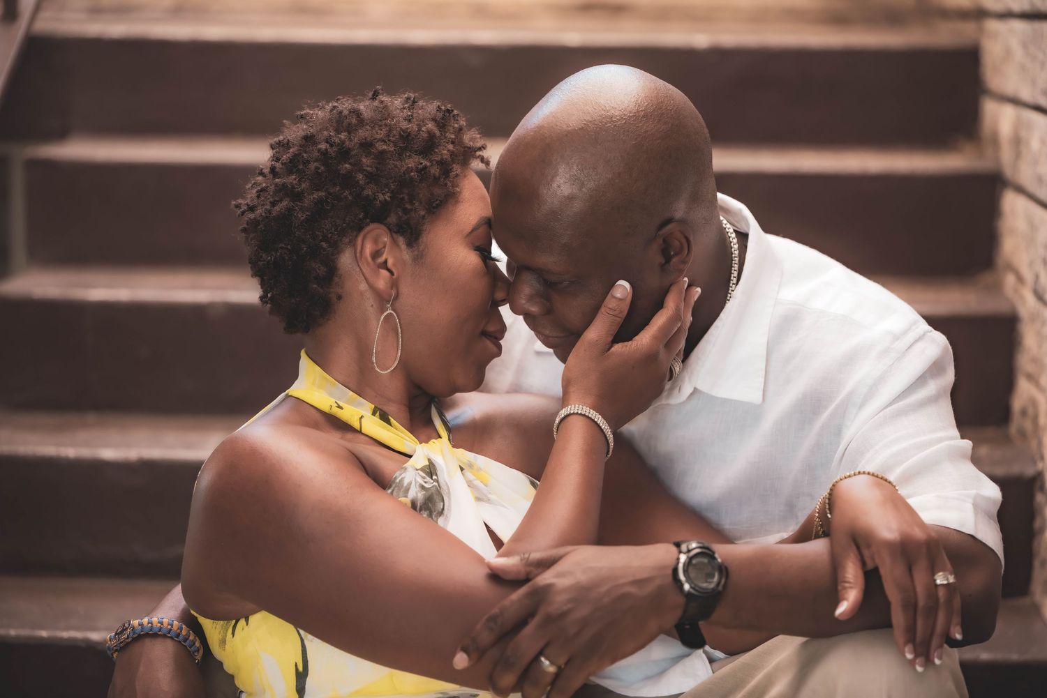 Intimate couple portrait on steps with warm lighting and close embrace.