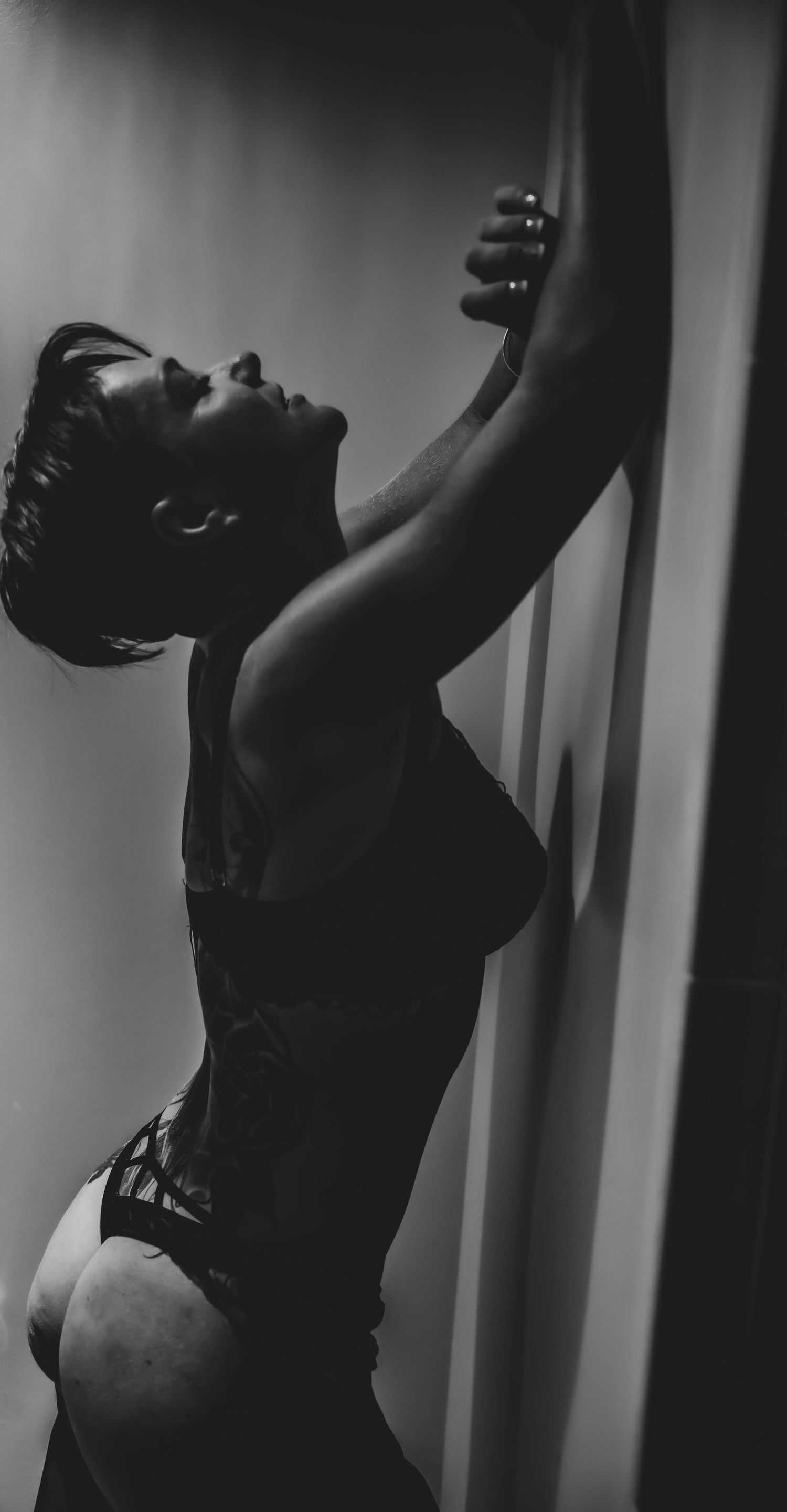 Artistic black and white boudoir photography with dramatic pose and lighting.