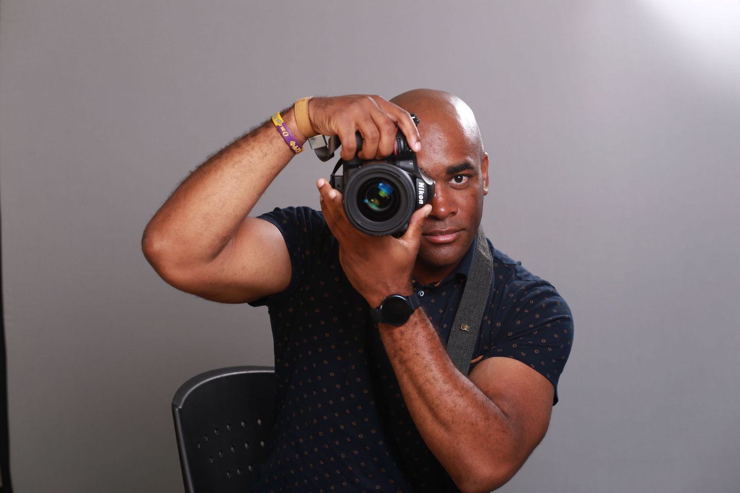 Photographer holding and looking through a professional camera in a studio setting.