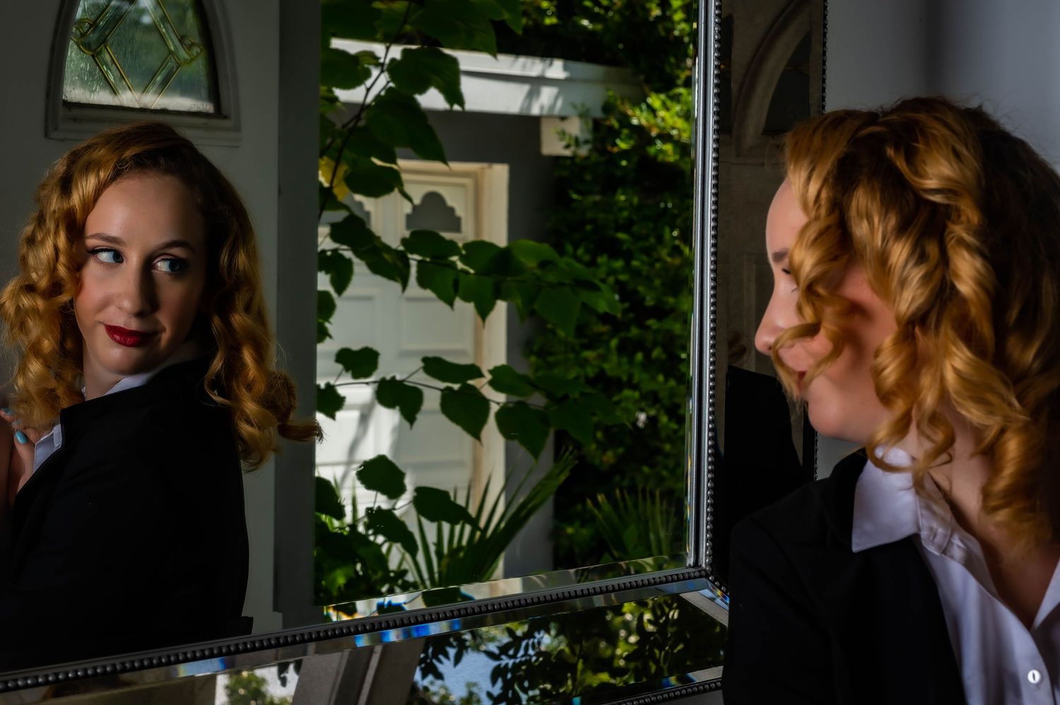 Indoor portrait with dramatic lighting and plants in background.