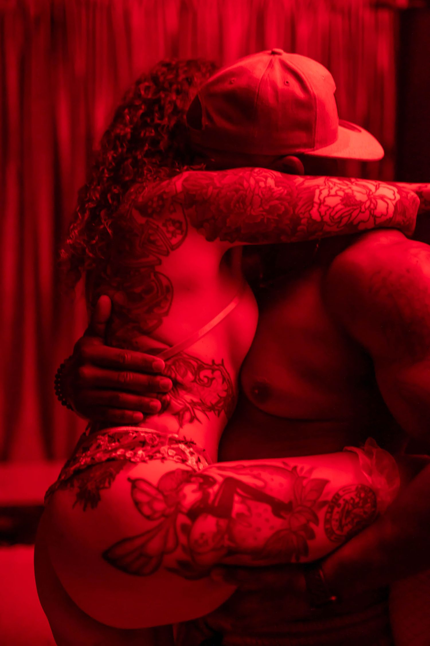 Artistic boudoir photo with red lighting and lace details creating a moody atmosphere.