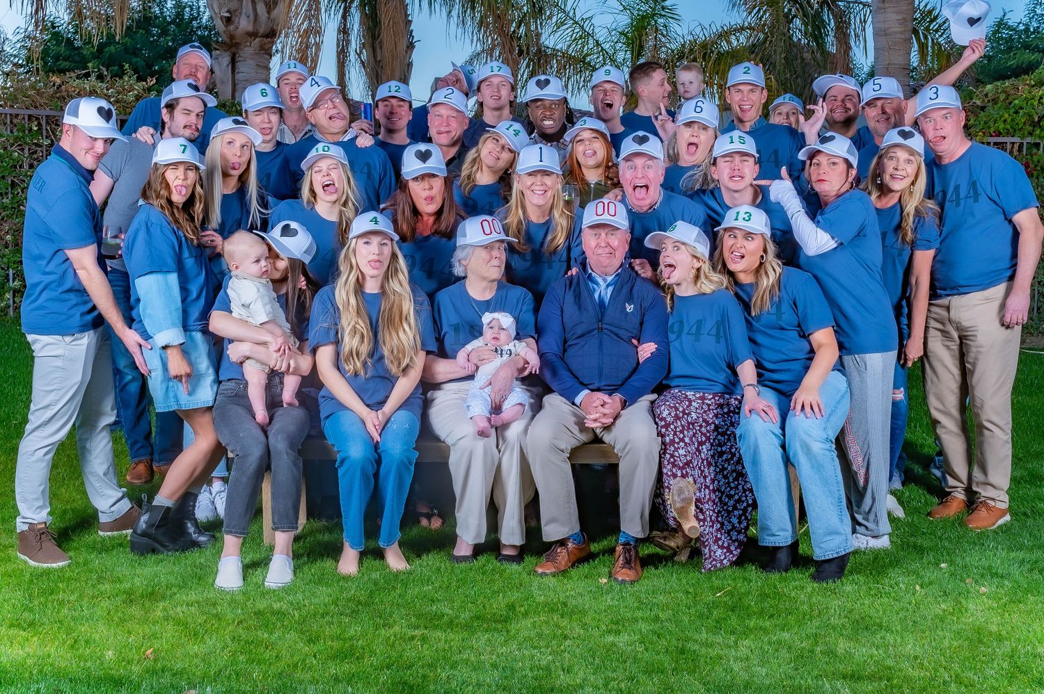 Large family group photo taken outdoors with everyone wearing coordinated blue and casual attire.