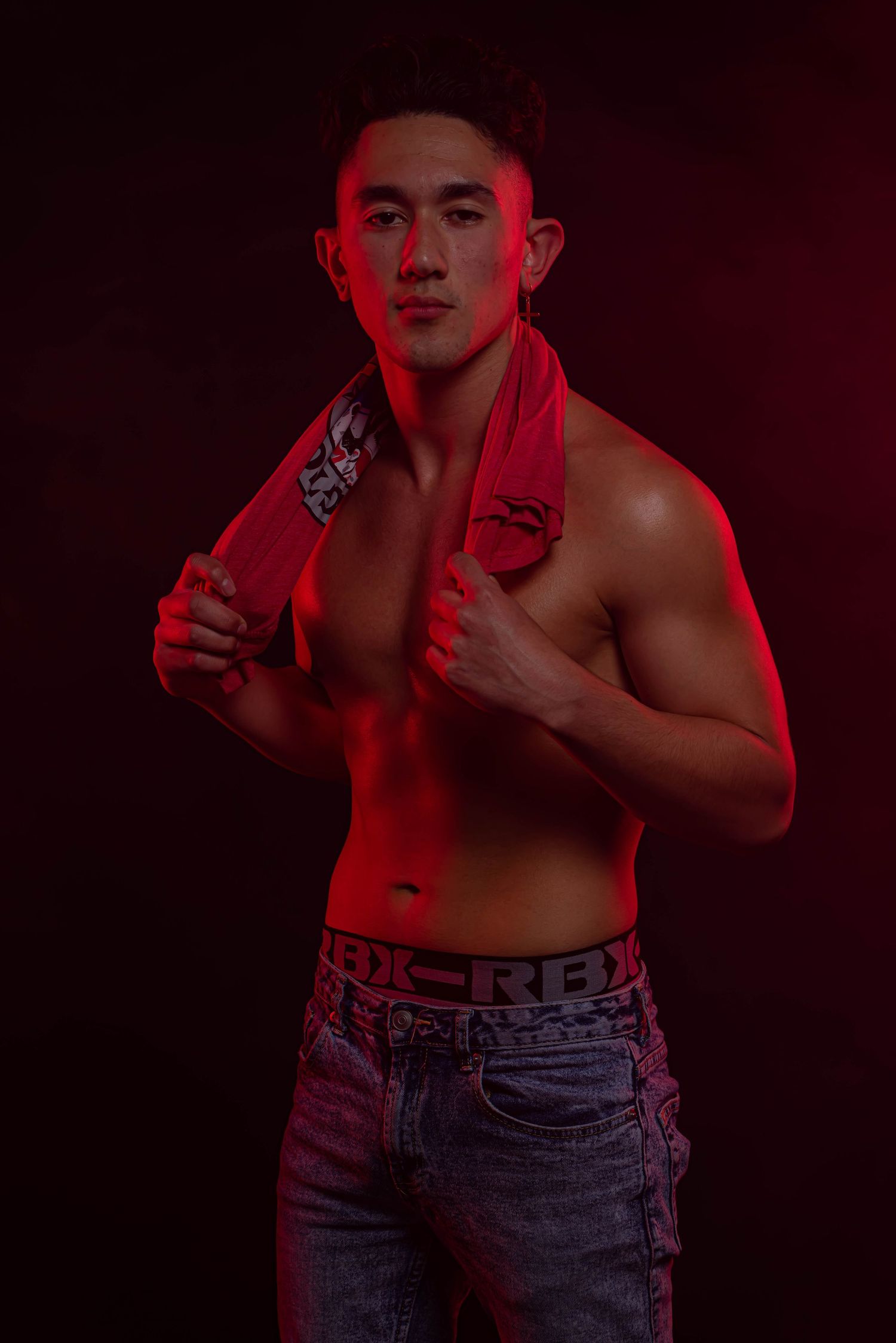 Athletic figure in jeans against dark red background.