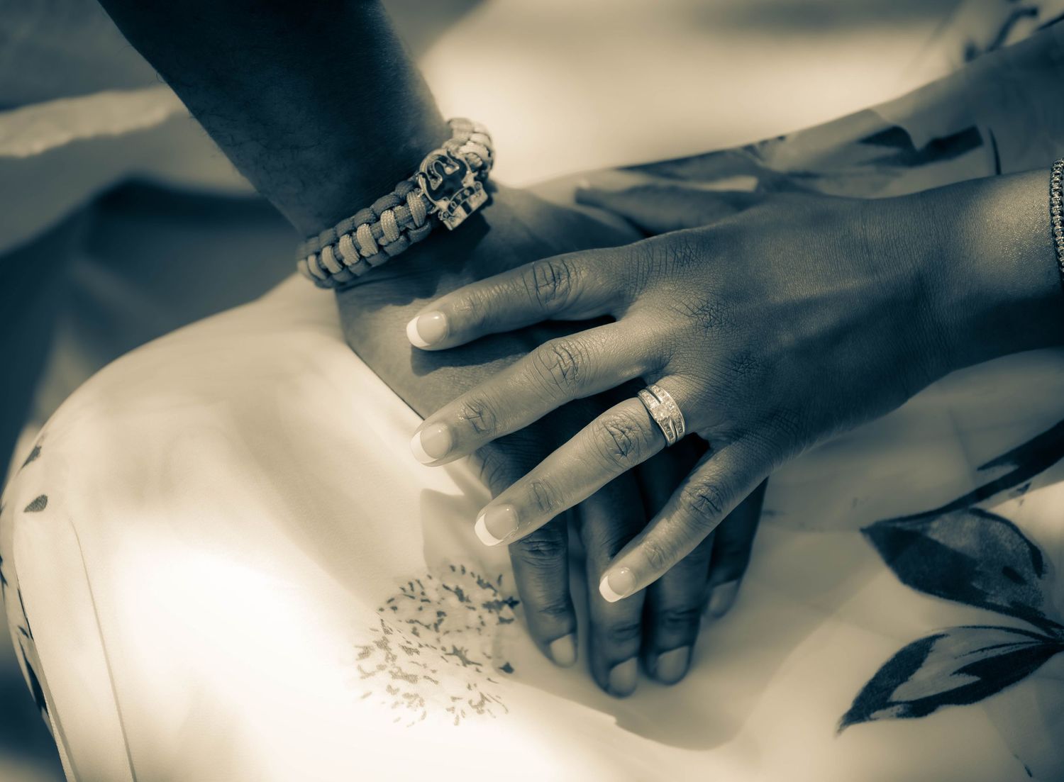 Close-up of hands wearing rings arranging decorative elements in a monochrome artistic style.