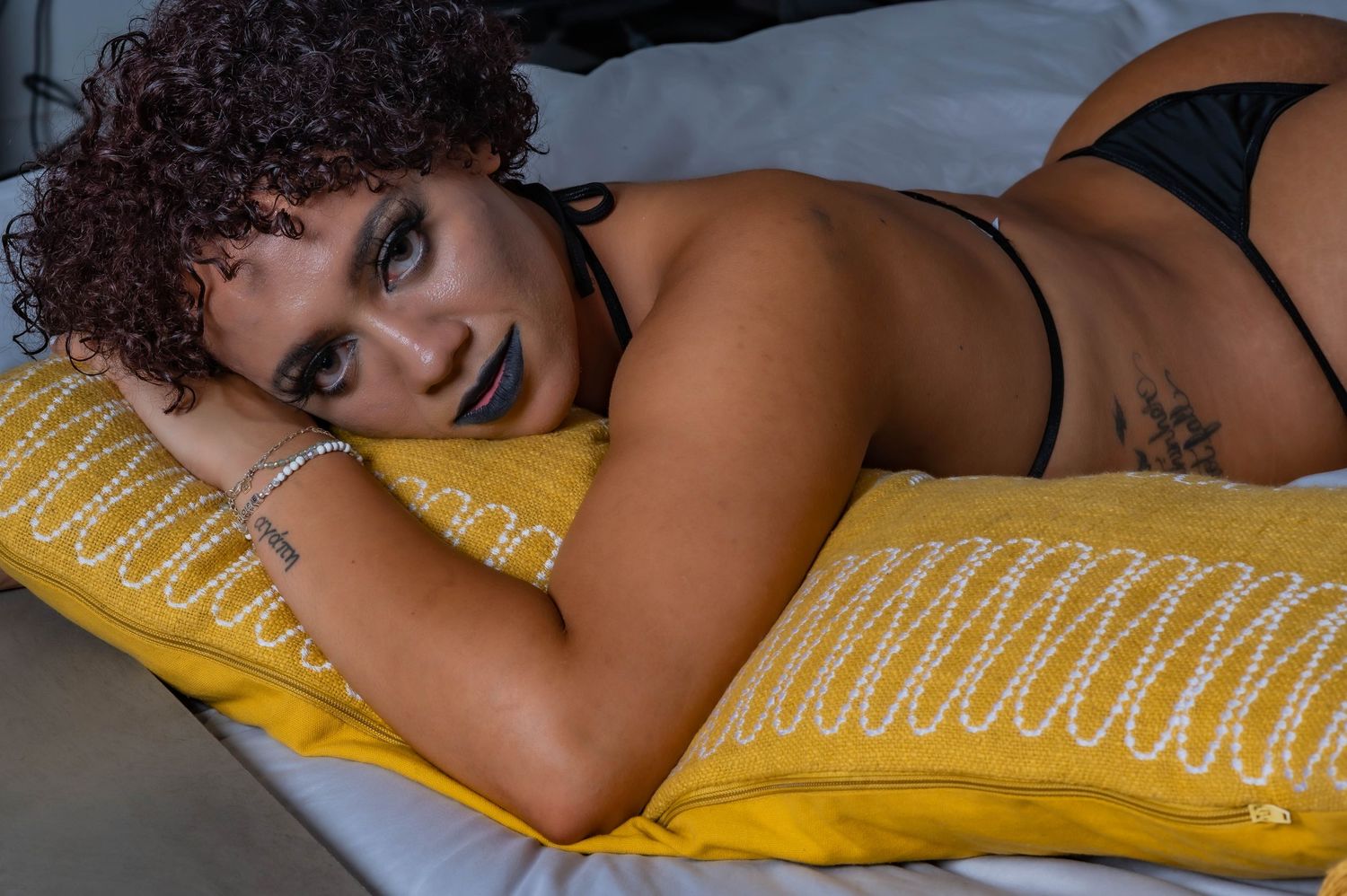 Intimate portrait session with natural curls on yellow pillow.