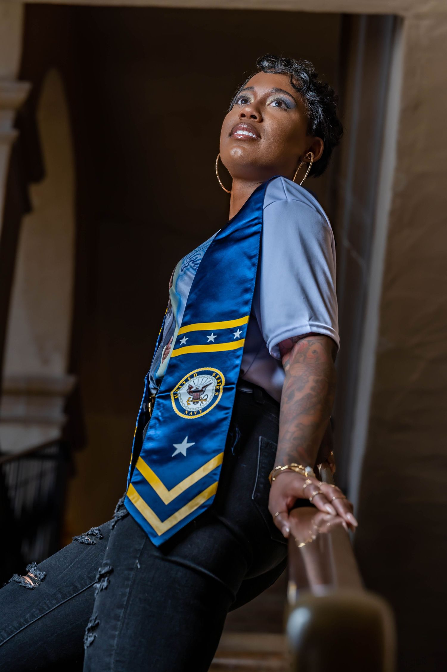 Person wearing blue and gold striped ceremonial sash posing confidently.