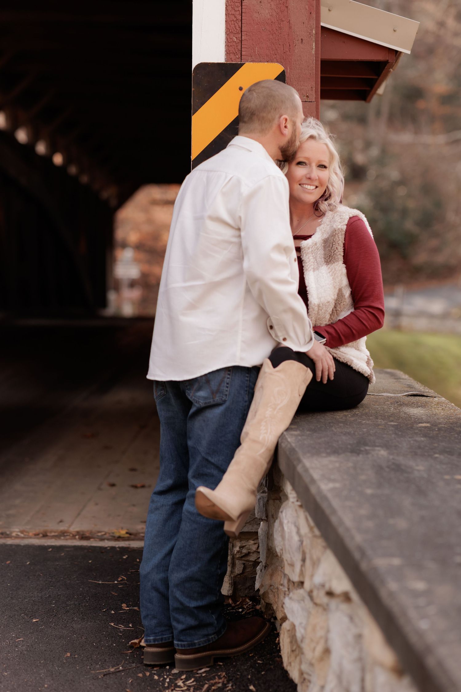 Two people sit close together on a stone ledge during an intimate outdoor photo session.