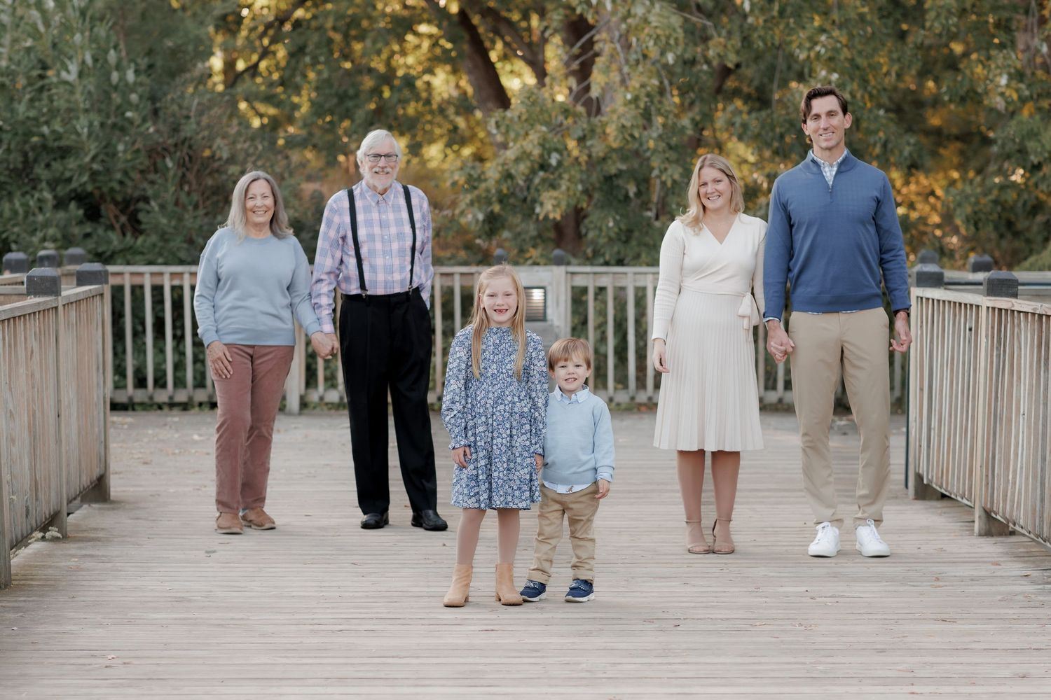 A series of candid family photos taken on a wooden bridge walkway during an outdoor photo session at sunset.