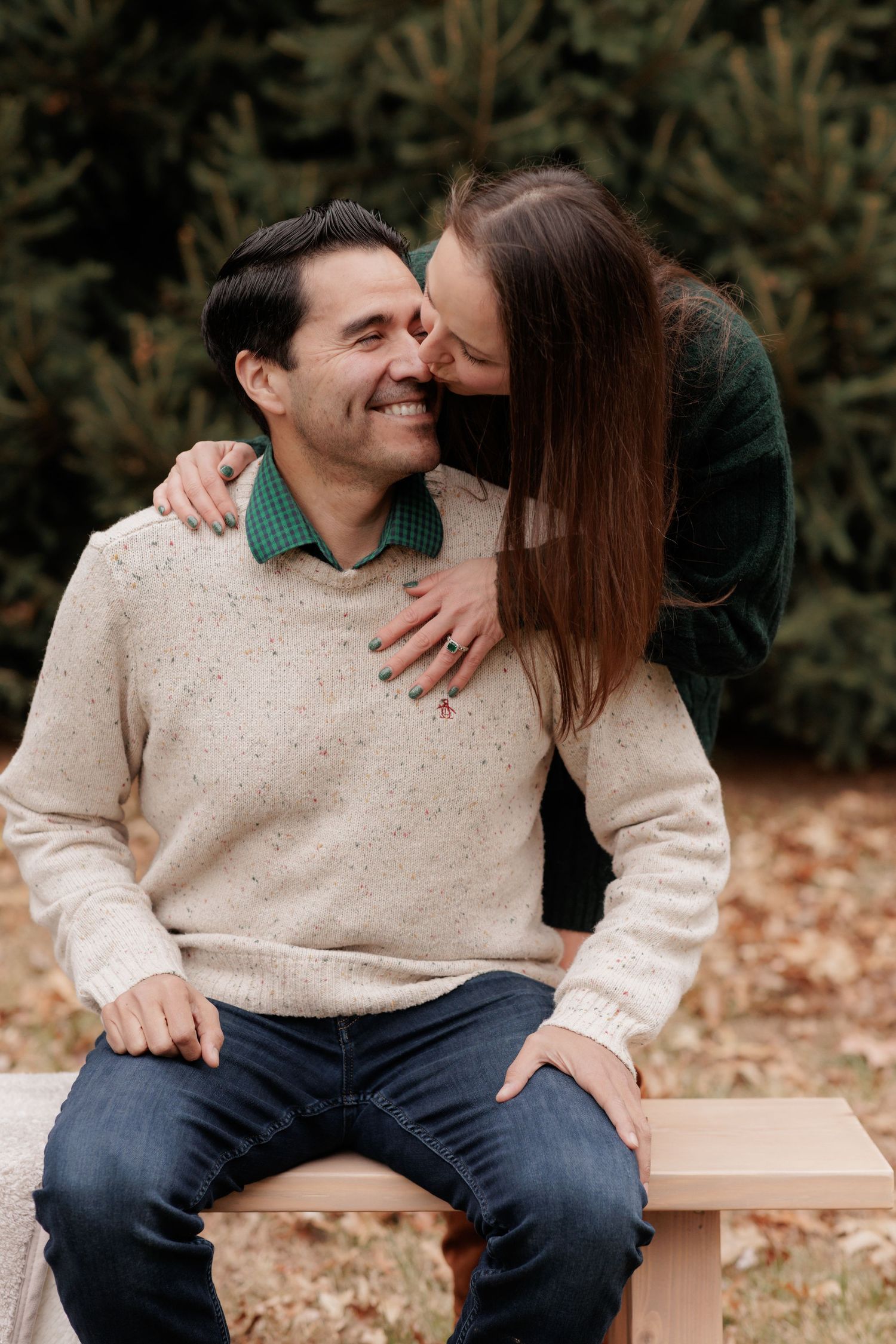 A couple in casual attire shares an intimate moment on a wooden bench.