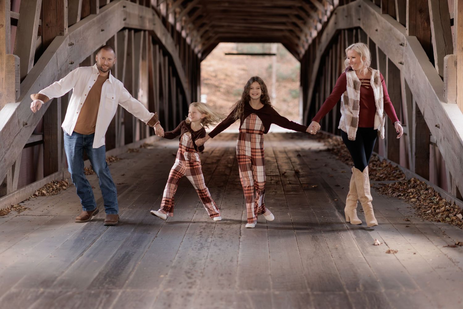 Family posing together under a rustic covered bridge during an outdoor photoshoot.