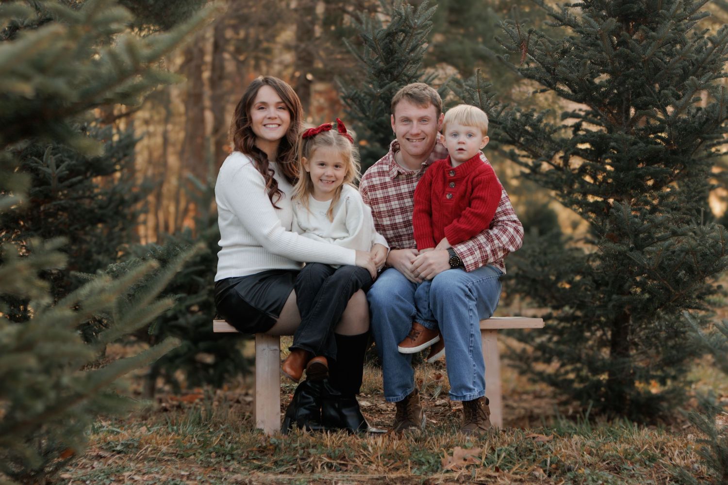 Family poses together among evergreen trees during a fall outdoor photo session.