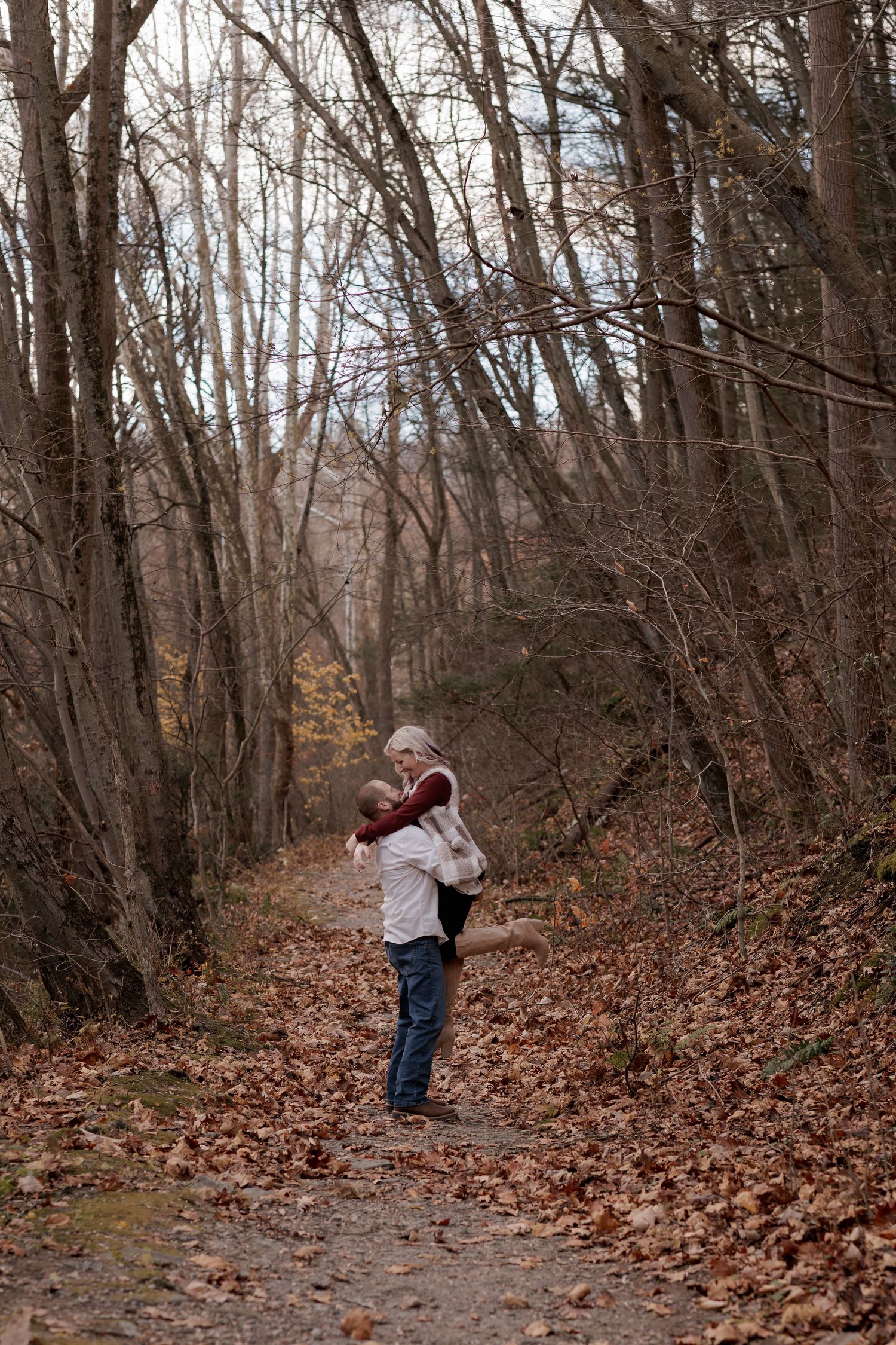A tender embrace on a leaf-covered forest path during autumn.
