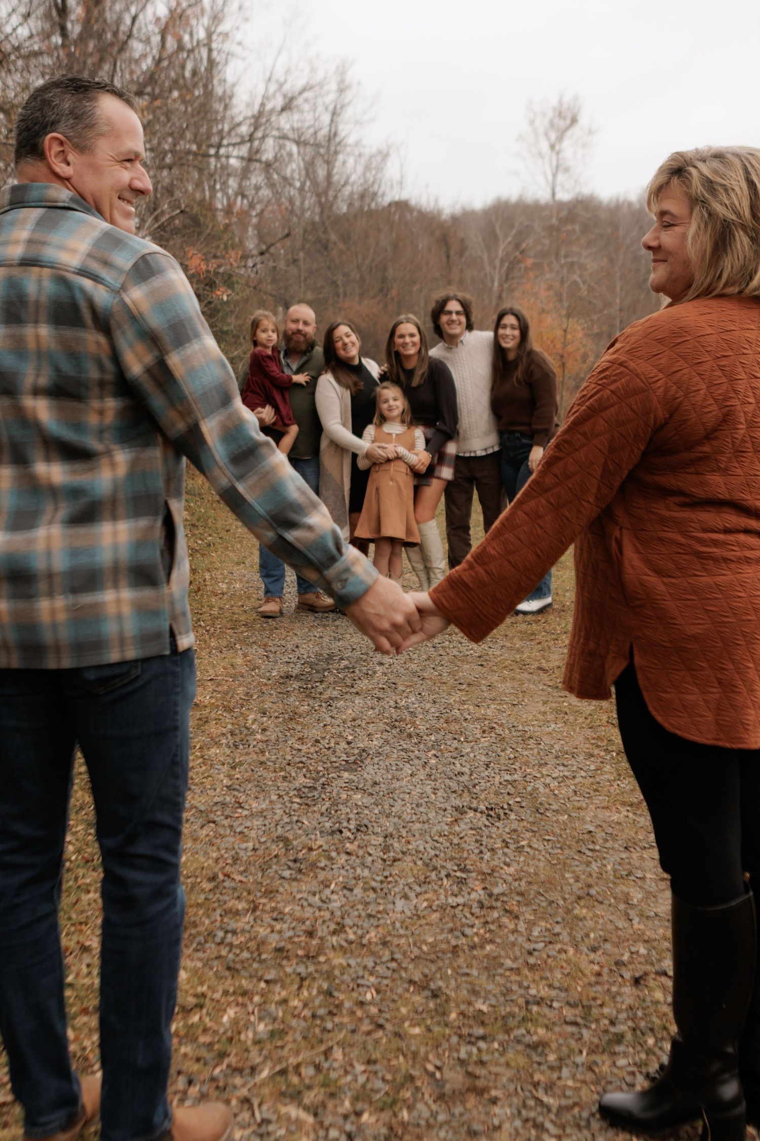 Family members hold hands in a line during outdoor autumn photoshoot.
