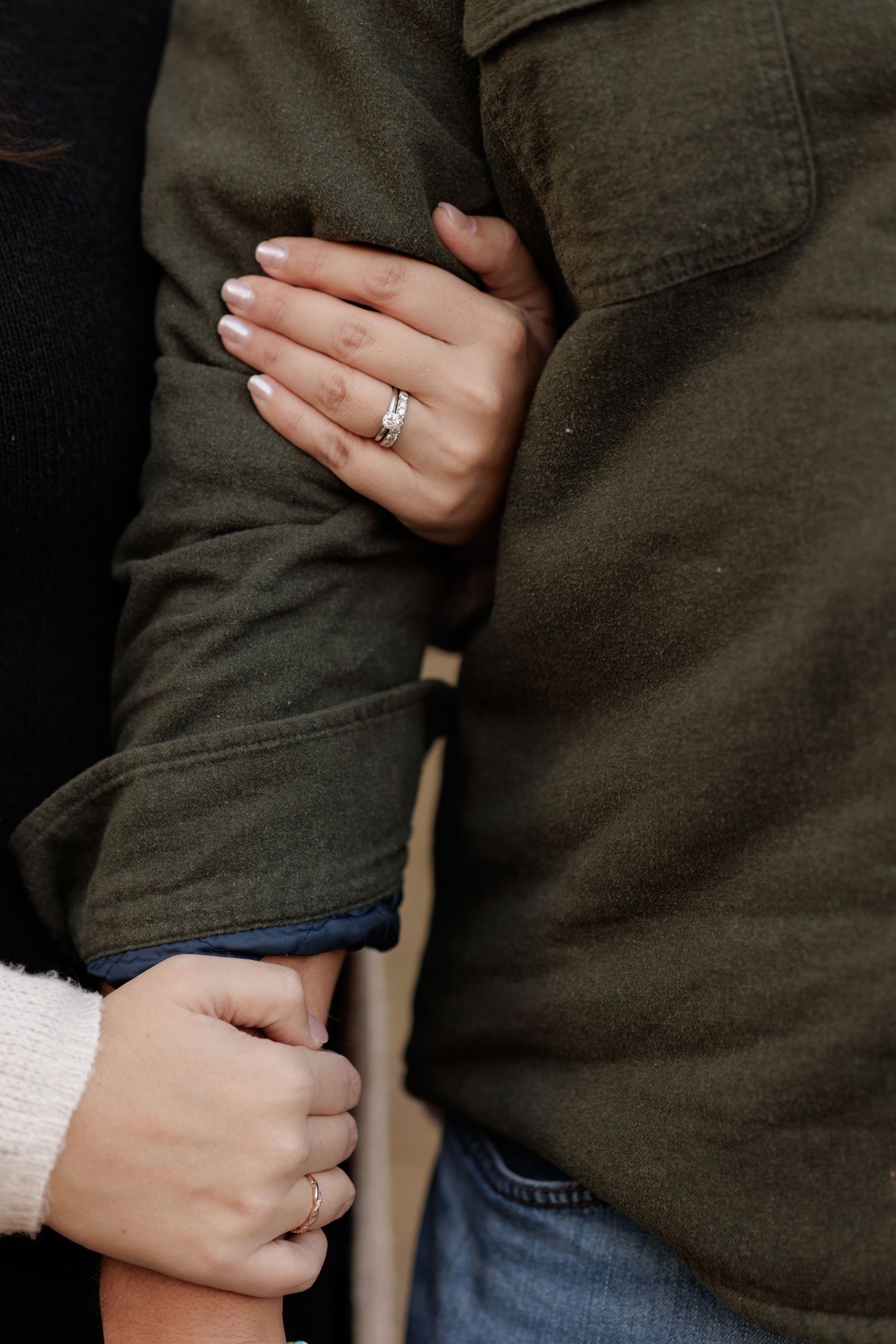 Close-up shots of hands with engagement rings against dark clothing.