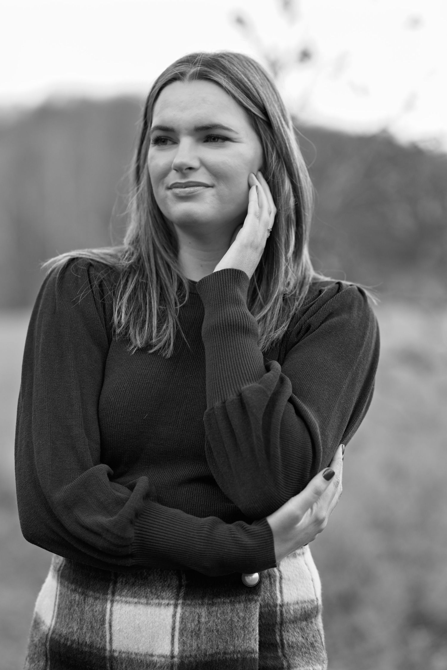 Black and white portrait of woman in dark sweater outdoors.