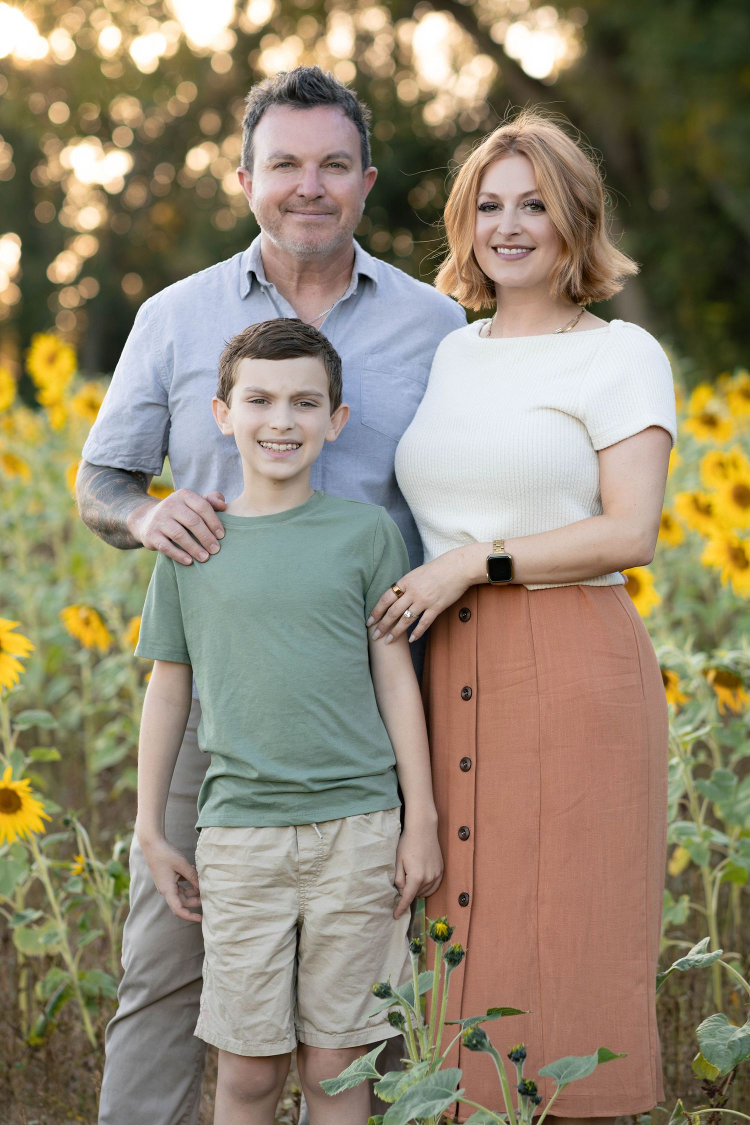 Family portrait in a blooming sunflower field during golden hour.