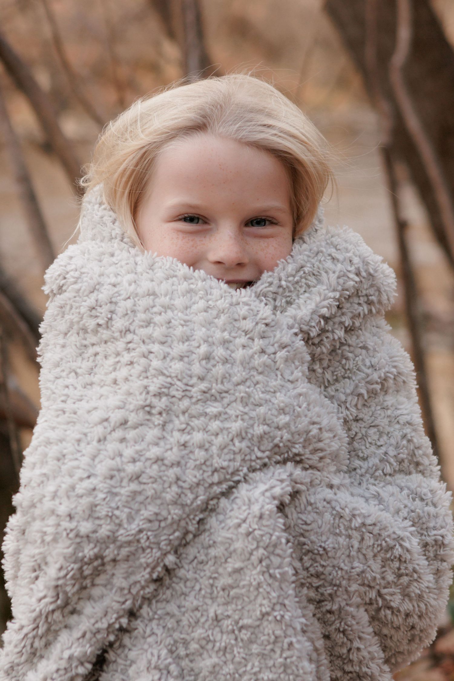 A cozy winter portrait wrapped in a fluffy white blanket.
