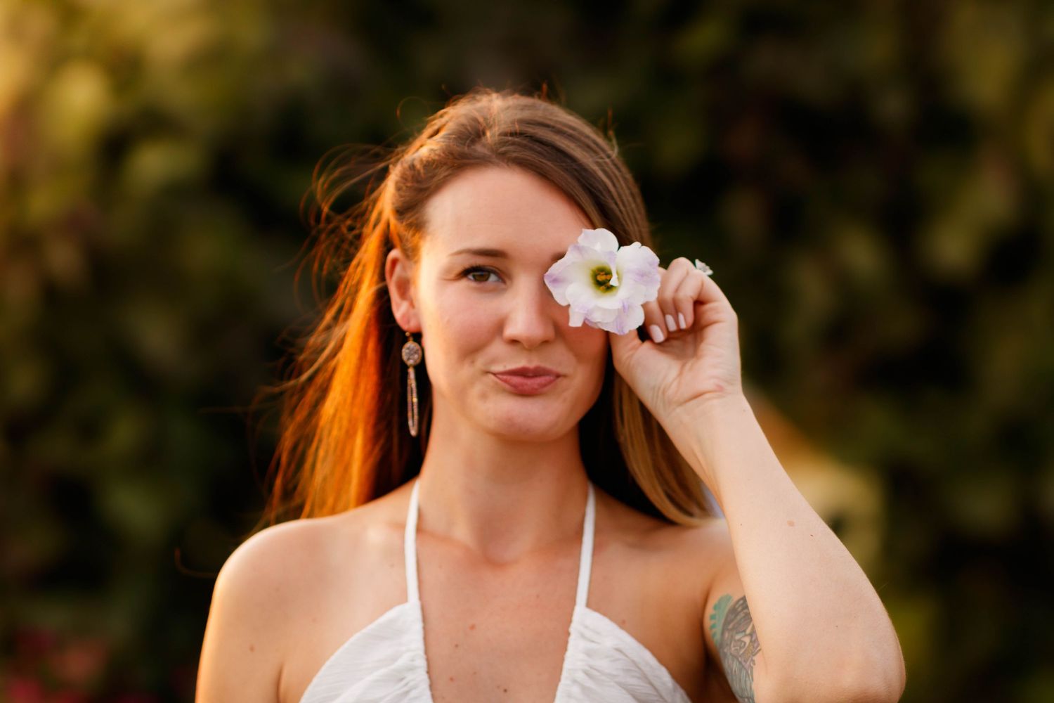 Portrait in nature with white flower and halter dress at golden hour.