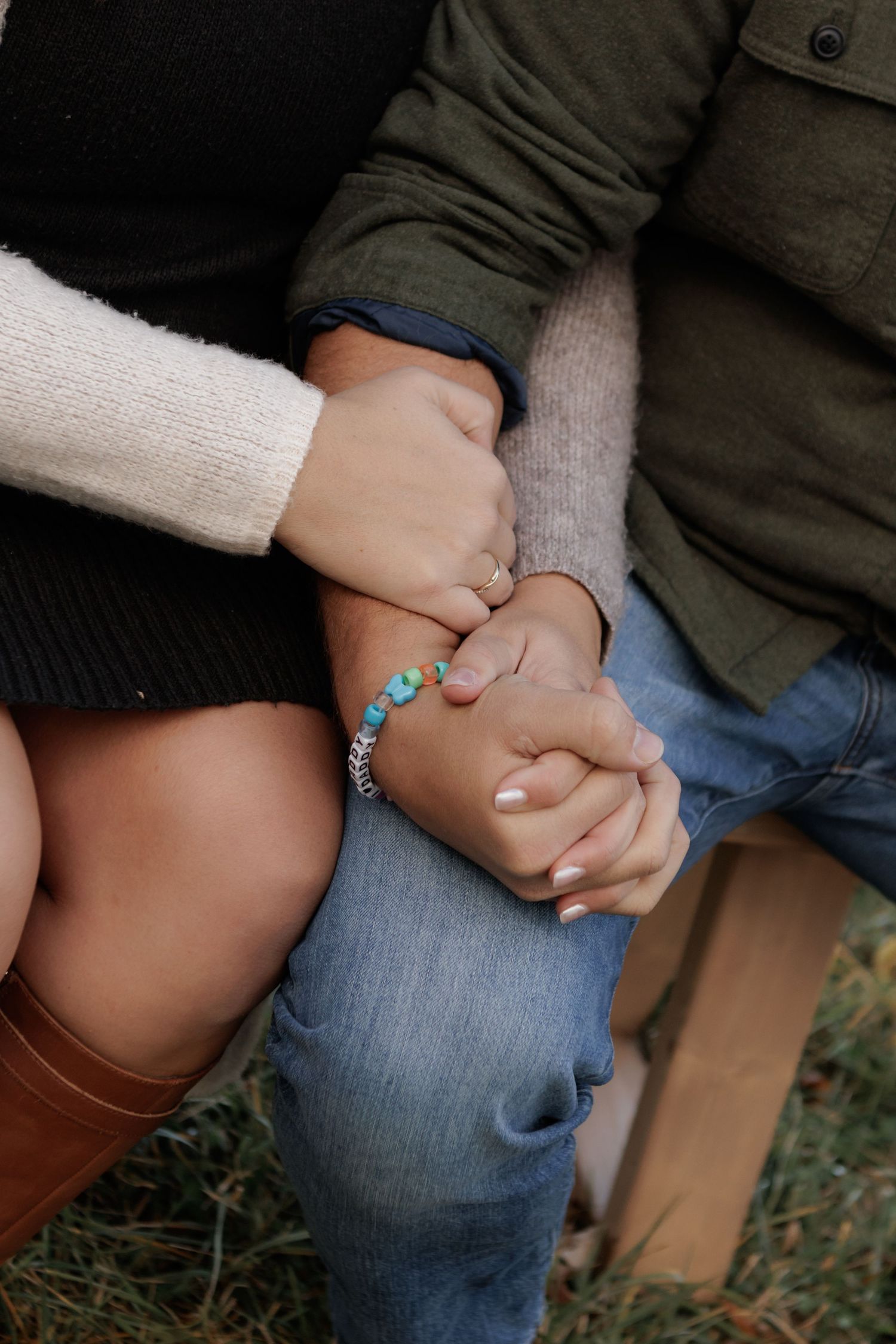 Close-up of intertwined hands wearing turquoise bracelet and casual attire.