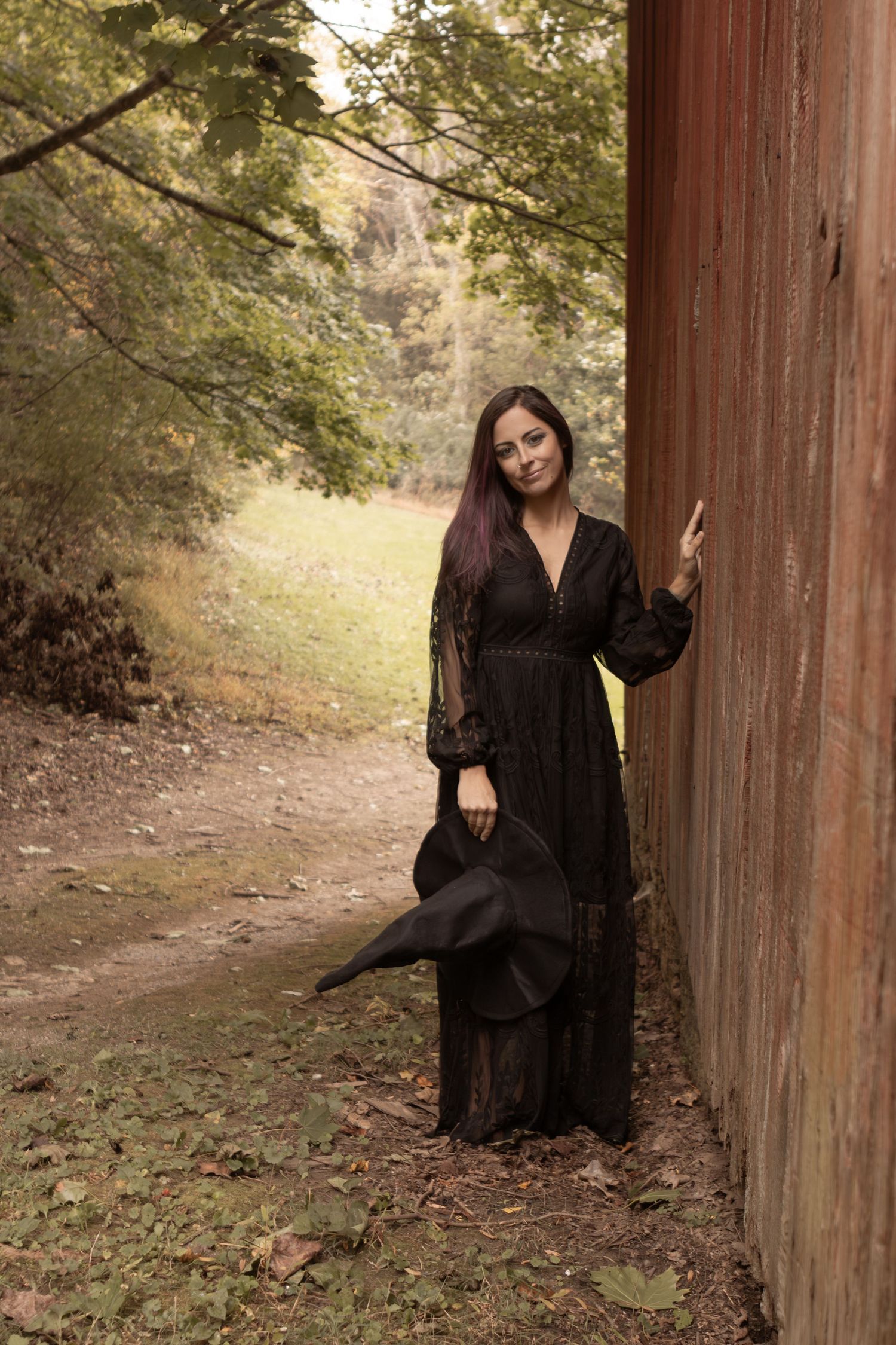 Dark-themed photoshoot featuring poses against a wooden column in an outdoor setting.