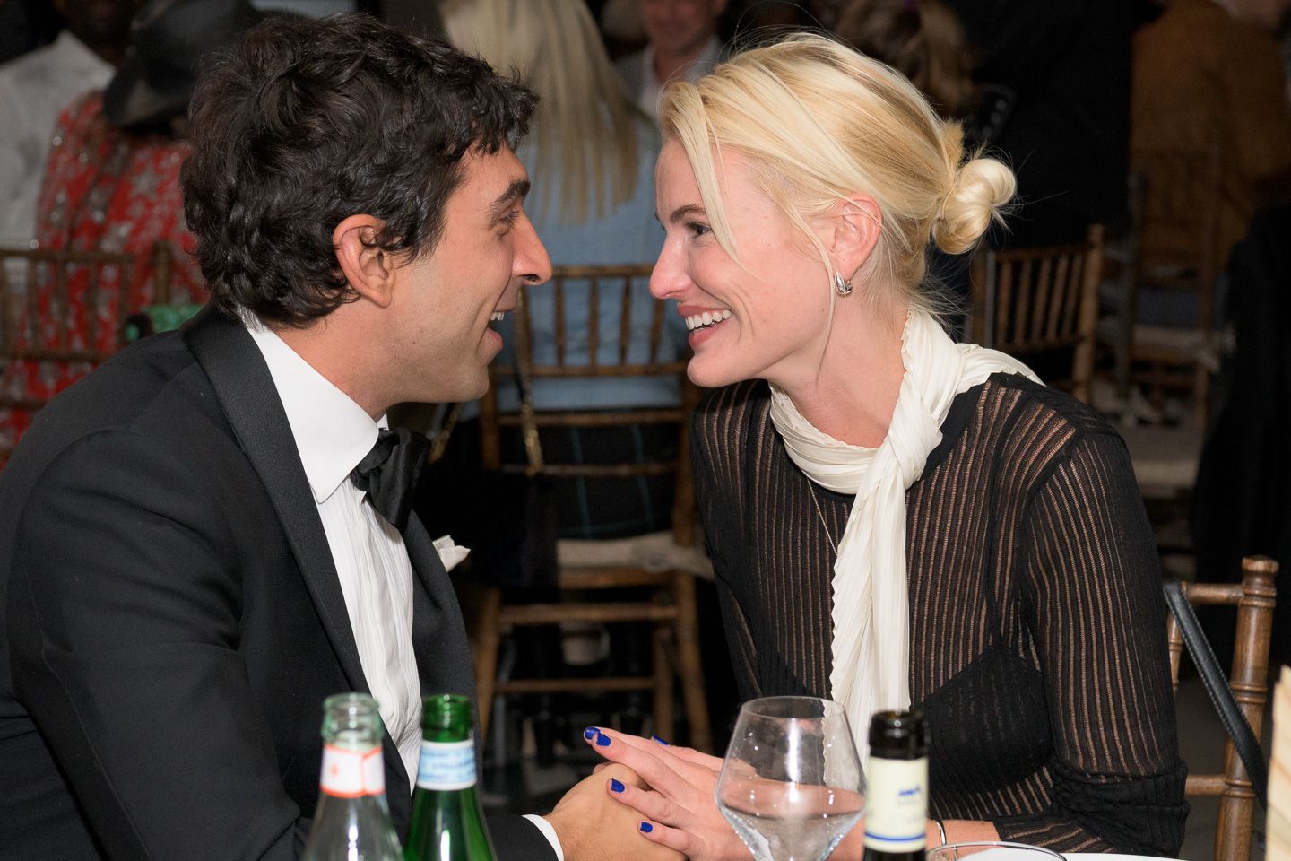 Couple in formal attire share an intimate conversation at an elegant gala dinner.