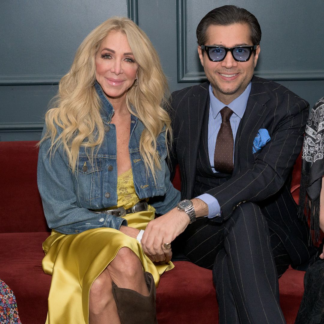 Blonde woman in denim jacket and man in pinstripe suit seated together at formal event.