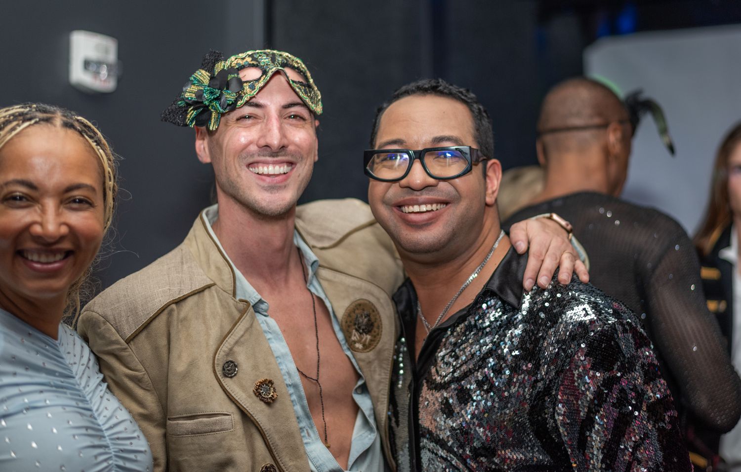Three friends smiling and posing together at a vibrant nightclub party event.
