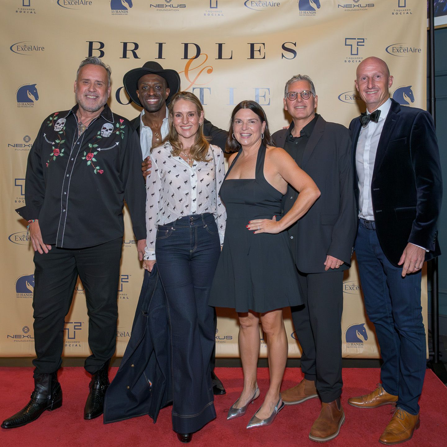 Group of six people posing on a red carpet at the Bridles event.