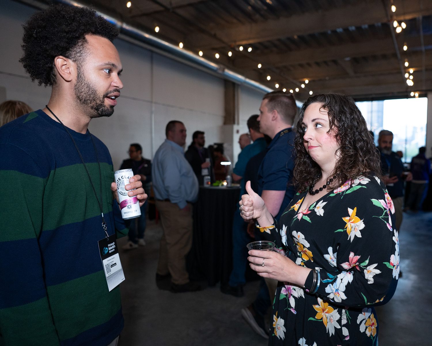 Man and woman networking at a casual professional event, each holding beverages.