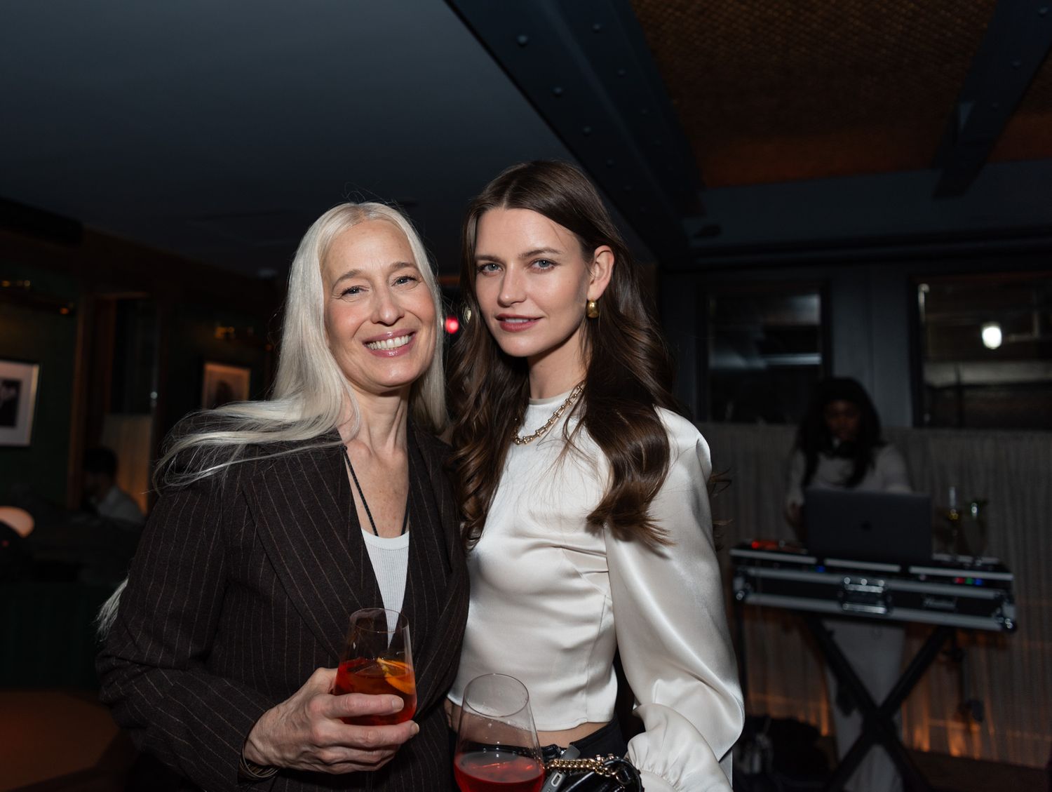 Two women posing together smiling at an elegant indoor evening event.