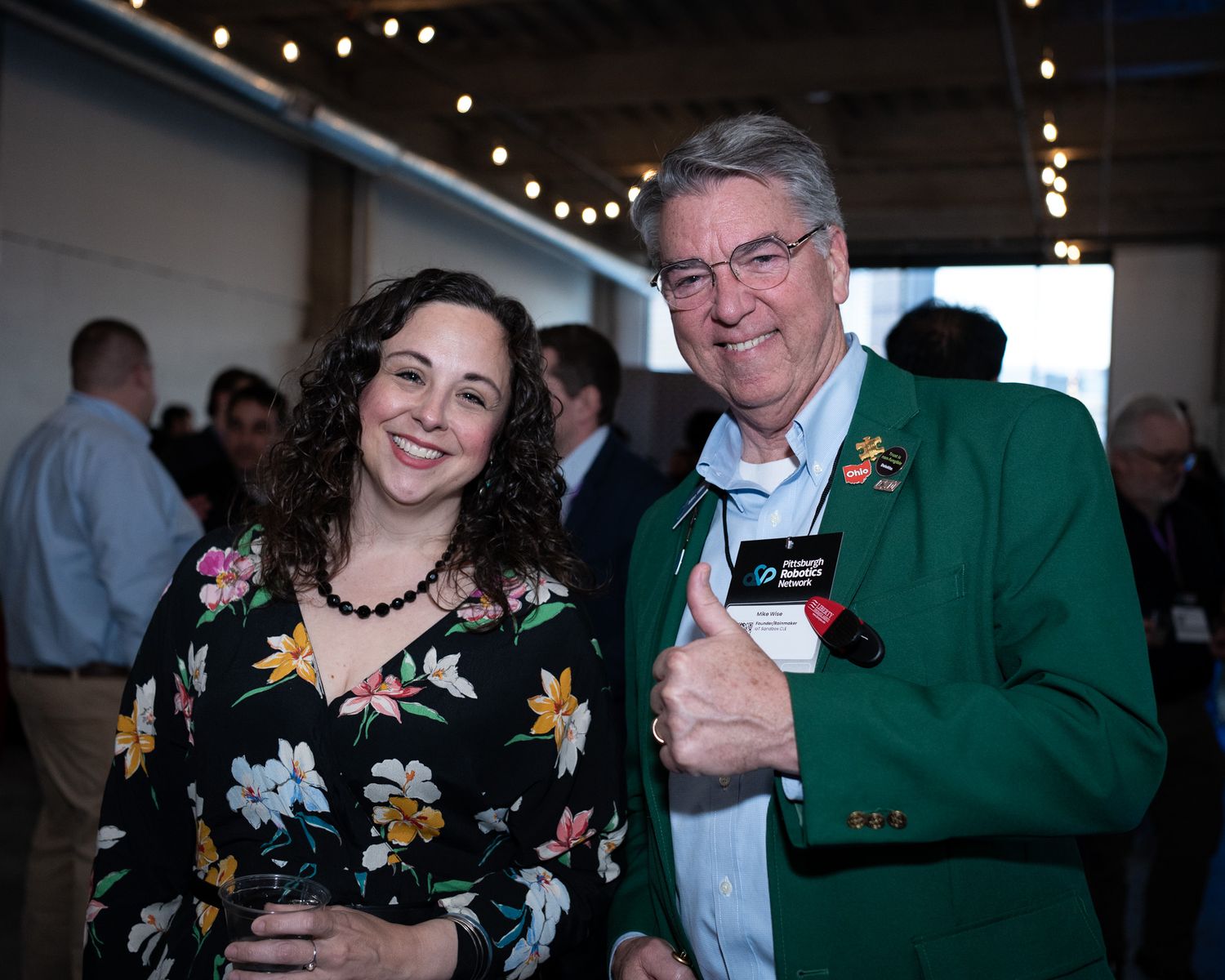 Smiling woman and man in green blazer posing together at an indoor networking event.
