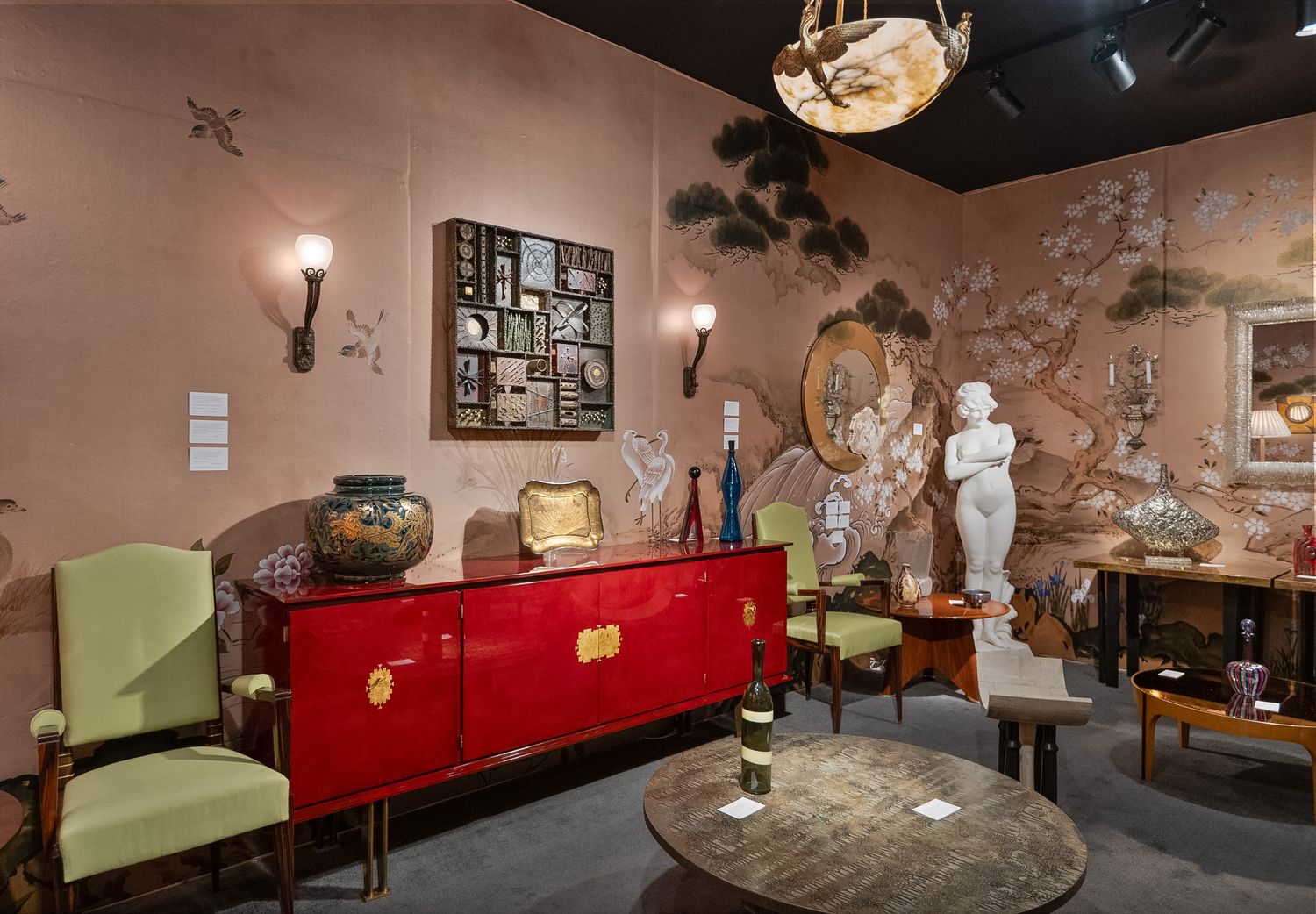 Antique showroom display featuring red lacquer sideboard, green chairs, and Asian-inspired wall mural.
