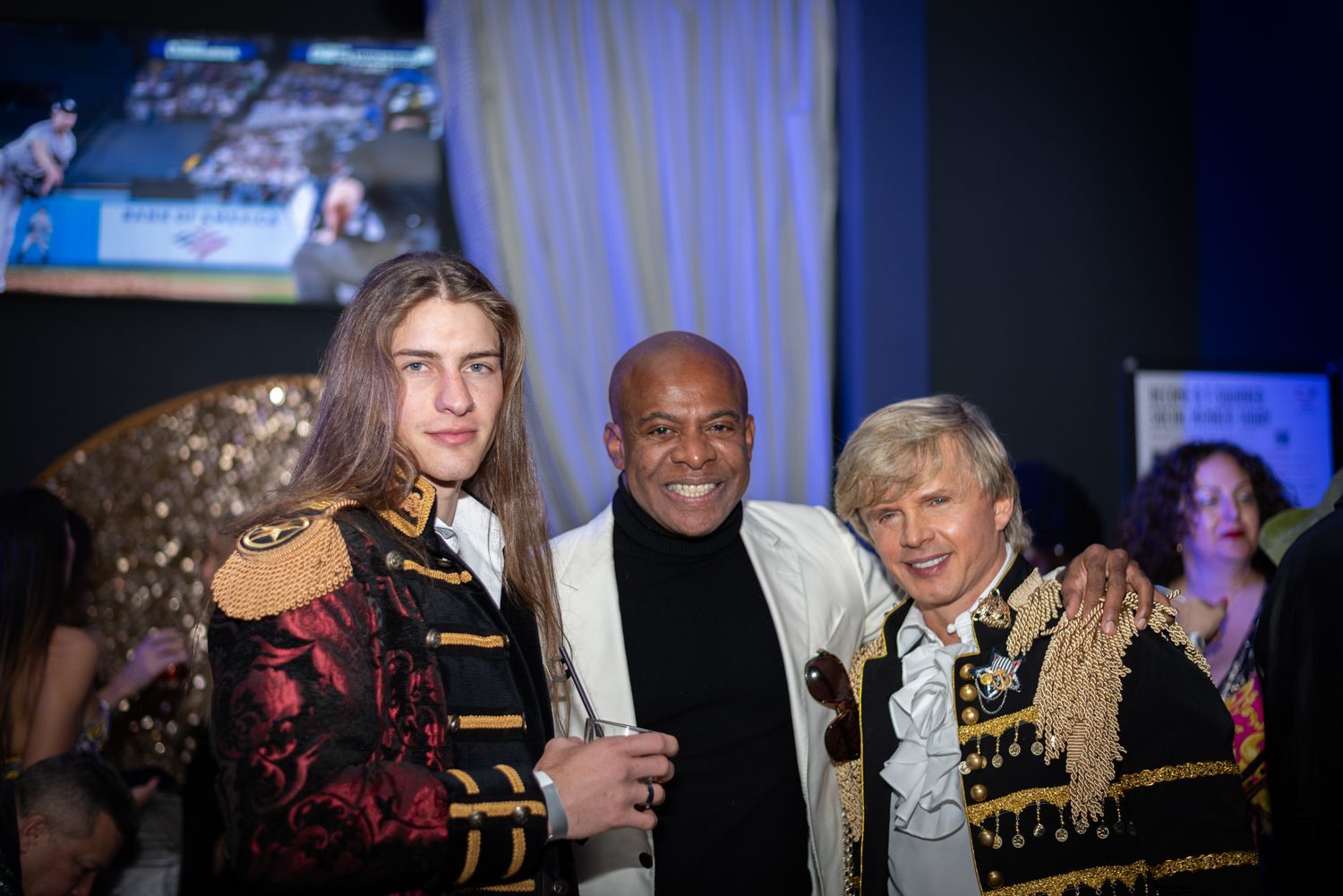 Three men in ornate jackets posing together at a formal entertainment event.