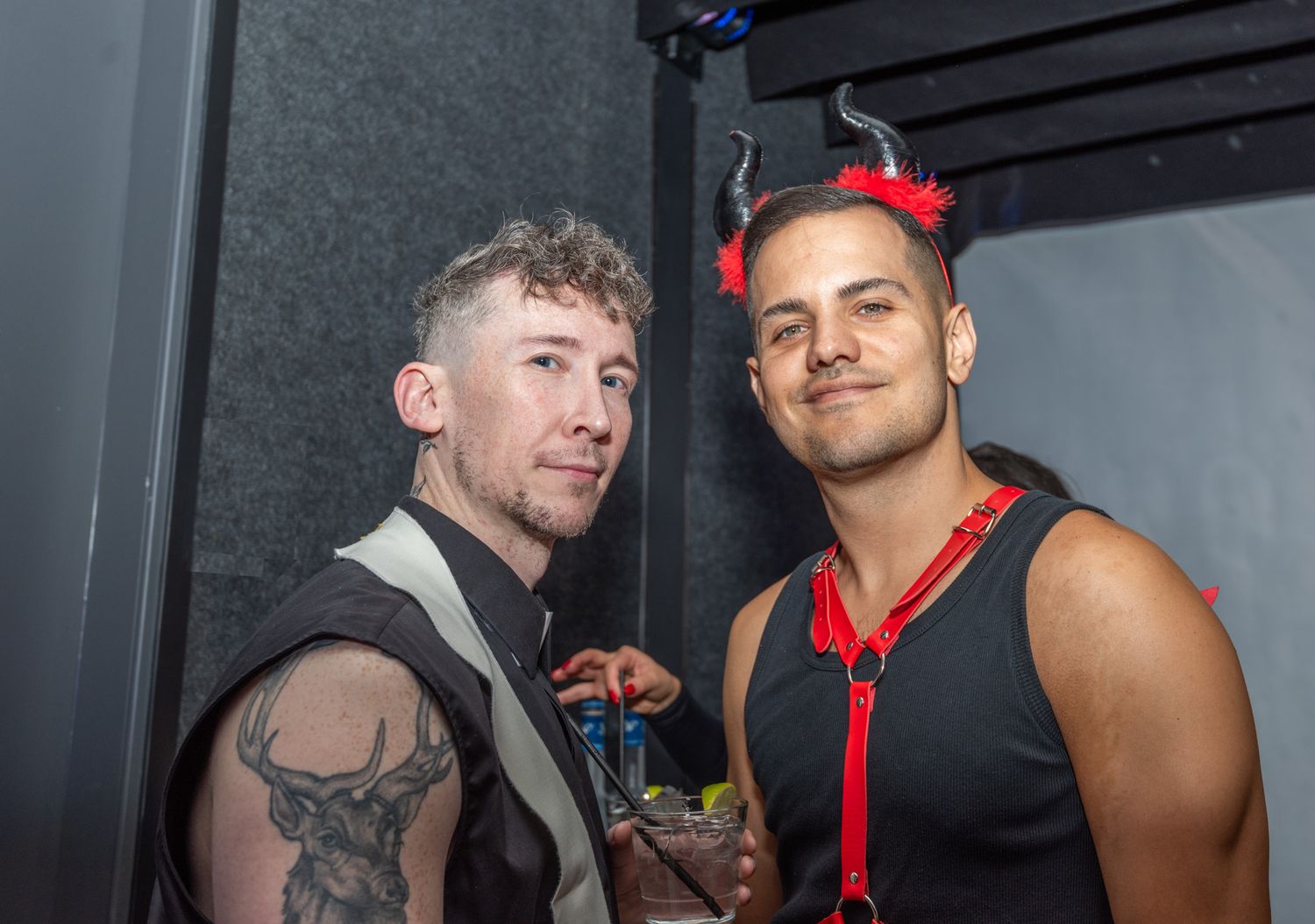 Two men in Halloween costumes, one as devil with red horns, posing.