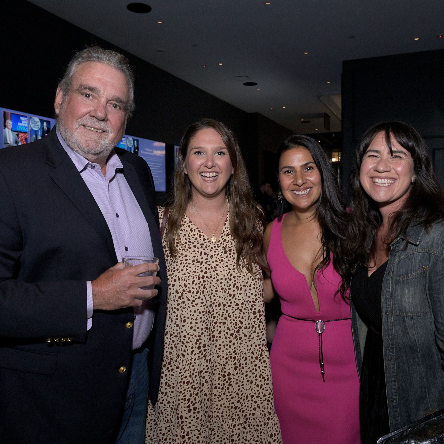 Group of four people smiling together at a social event in a modern venue.