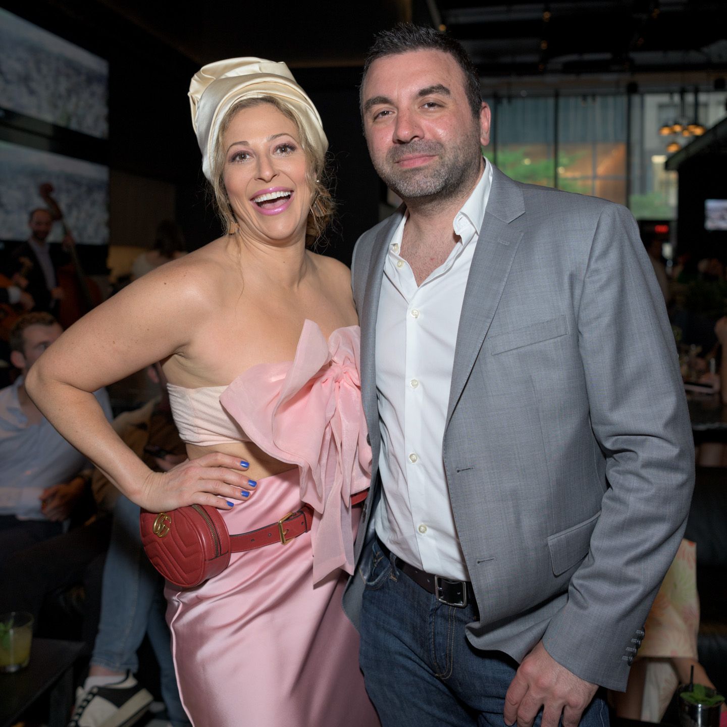 A woman in a pink strapless gown and a man in a grey blazer pose together at a formal event.