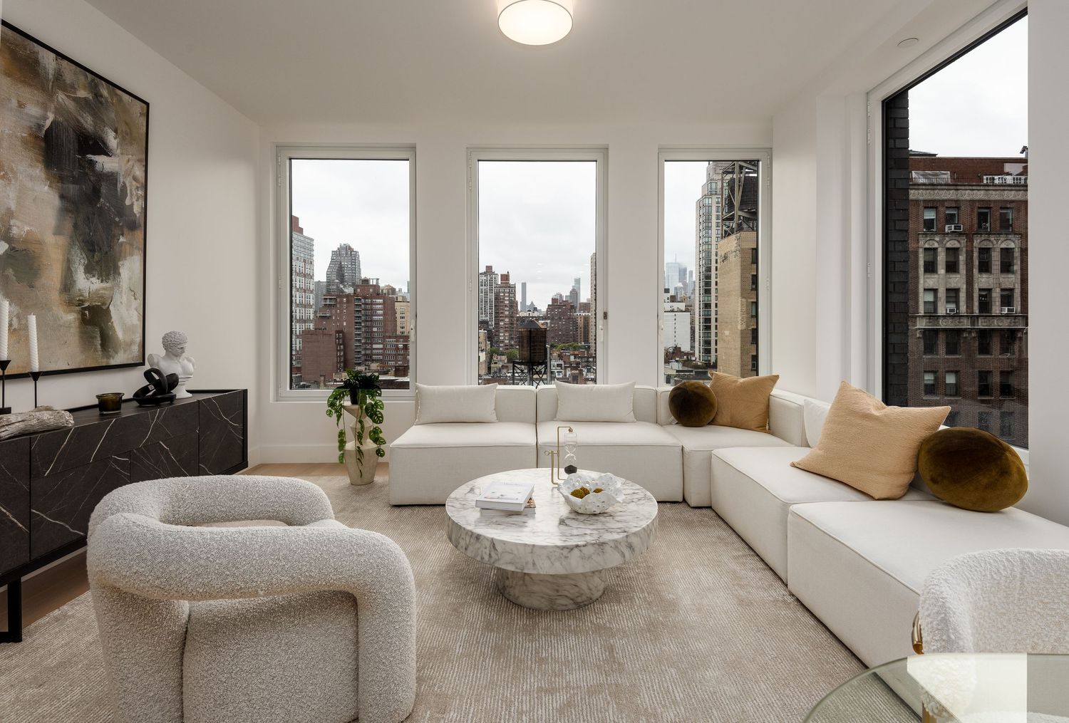 Modern luxury apartment living room with white sectional sofa and city skyline views.