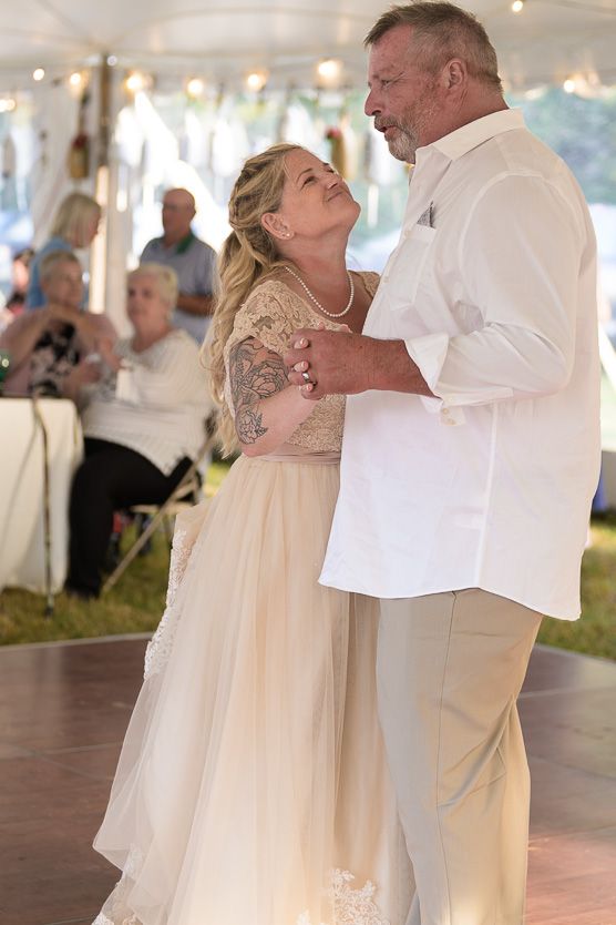 Bride and father share emotional first dance under white tent at outdoor wedding reception.
